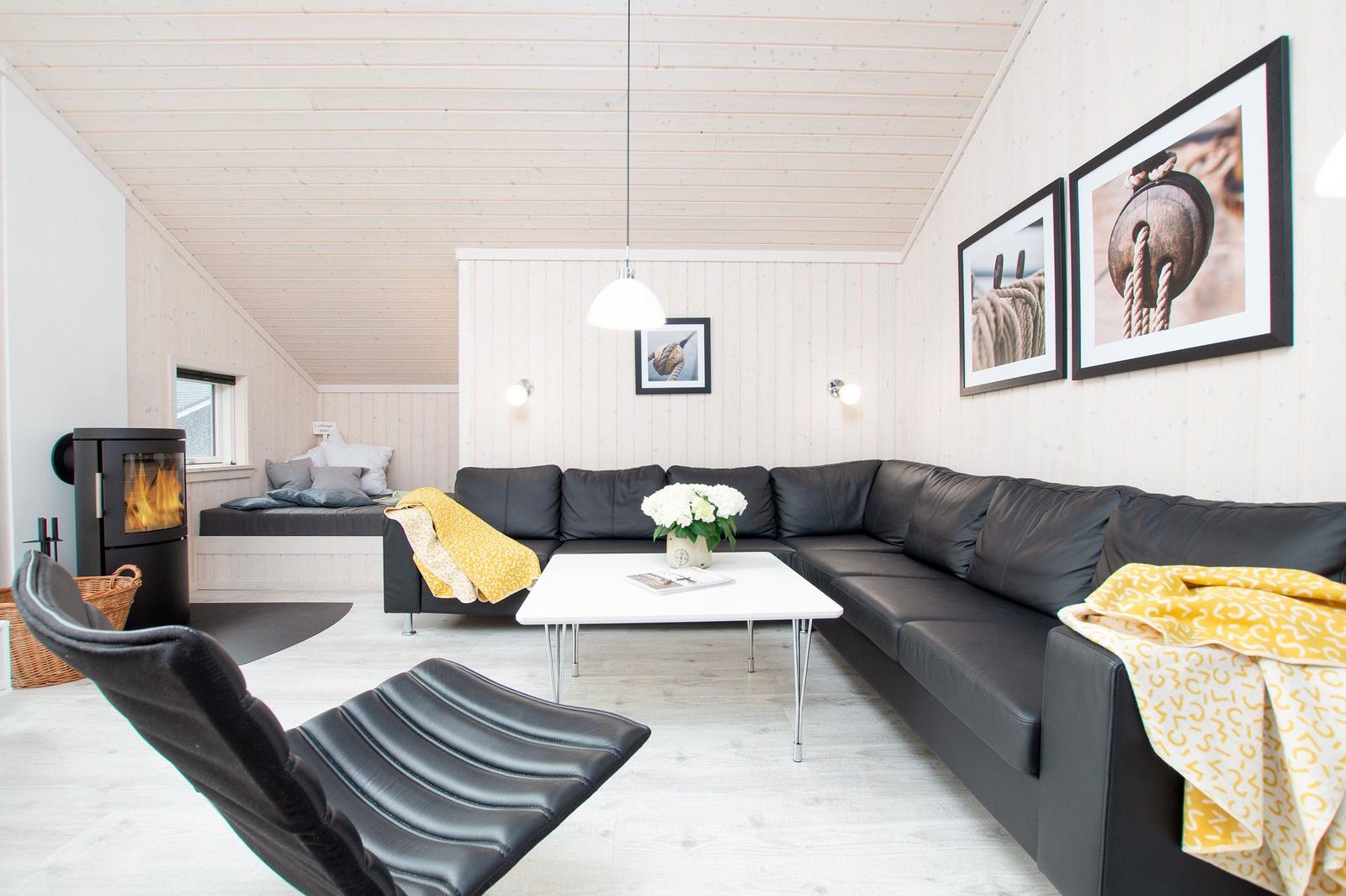 Wohnzimmer mit schwarzer Couch, weißem Tisch und Kamin.