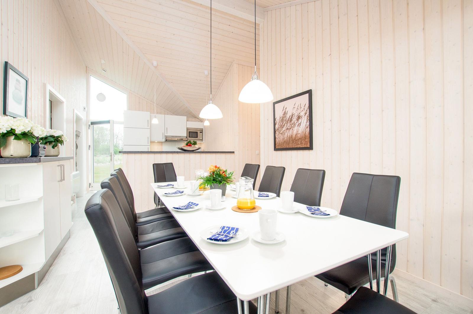Essbereich mit Tisch und Stühlen, Küche im Hintergrund, Holzwände und Decke.