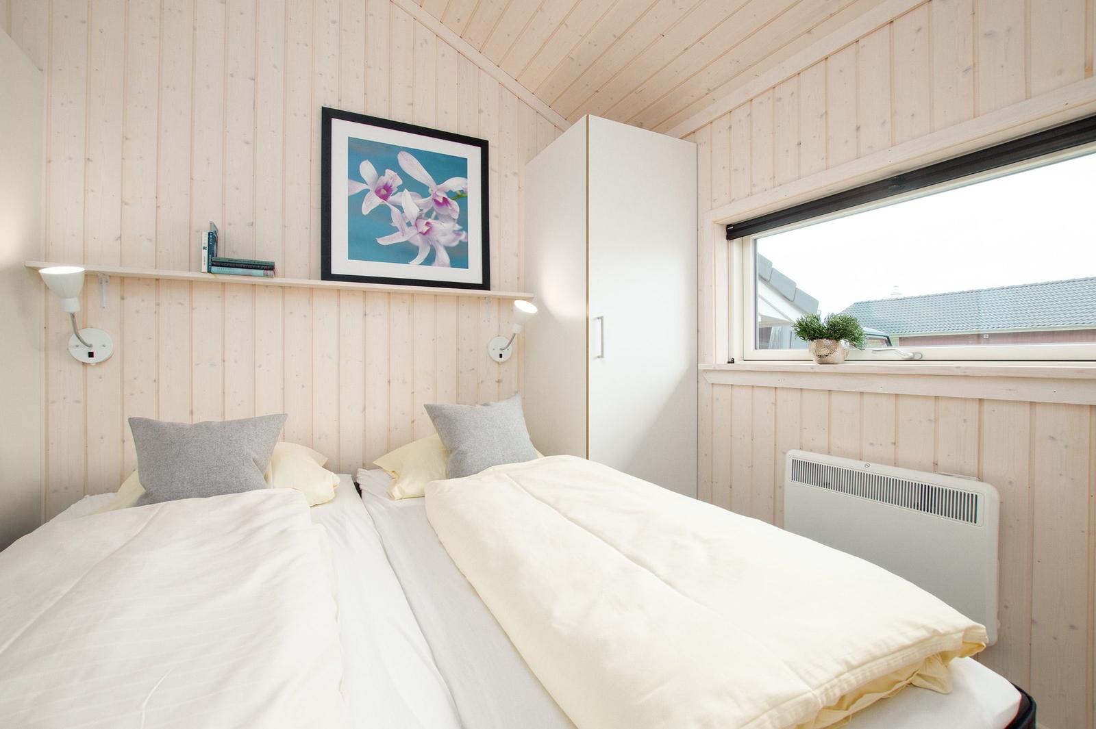 Zwei Betten mit weißen Bettwäsche, Wandbild und Fenster mit Pflanze.