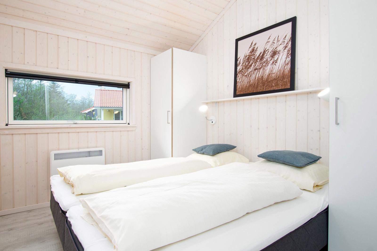 Schlafzimmer mit Doppelbett, Fenster und Wandbild.