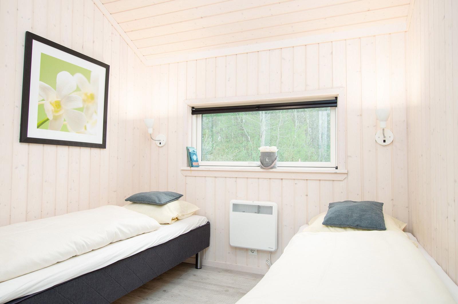 Zwei Einzelbetten, Fenster mit Waldblick, Wandbild und Heizung.