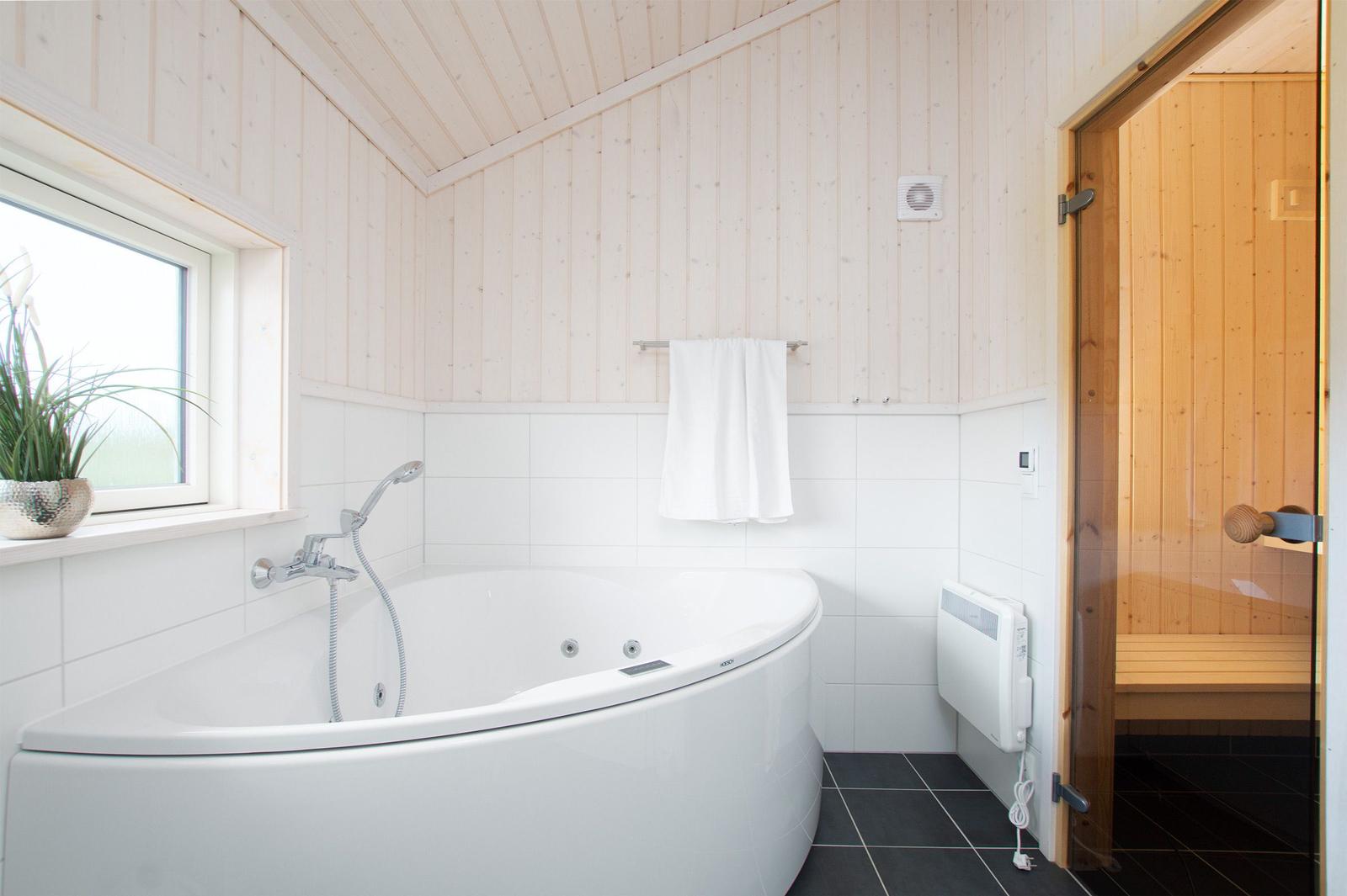 Bad mit Whirlpool, Fenster und Sauna im Hintergrund.