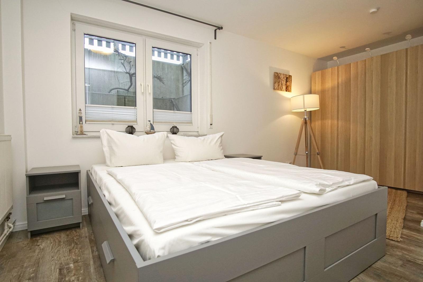 Schlafzimmer mit Doppelbett, Fenster und Holzwand