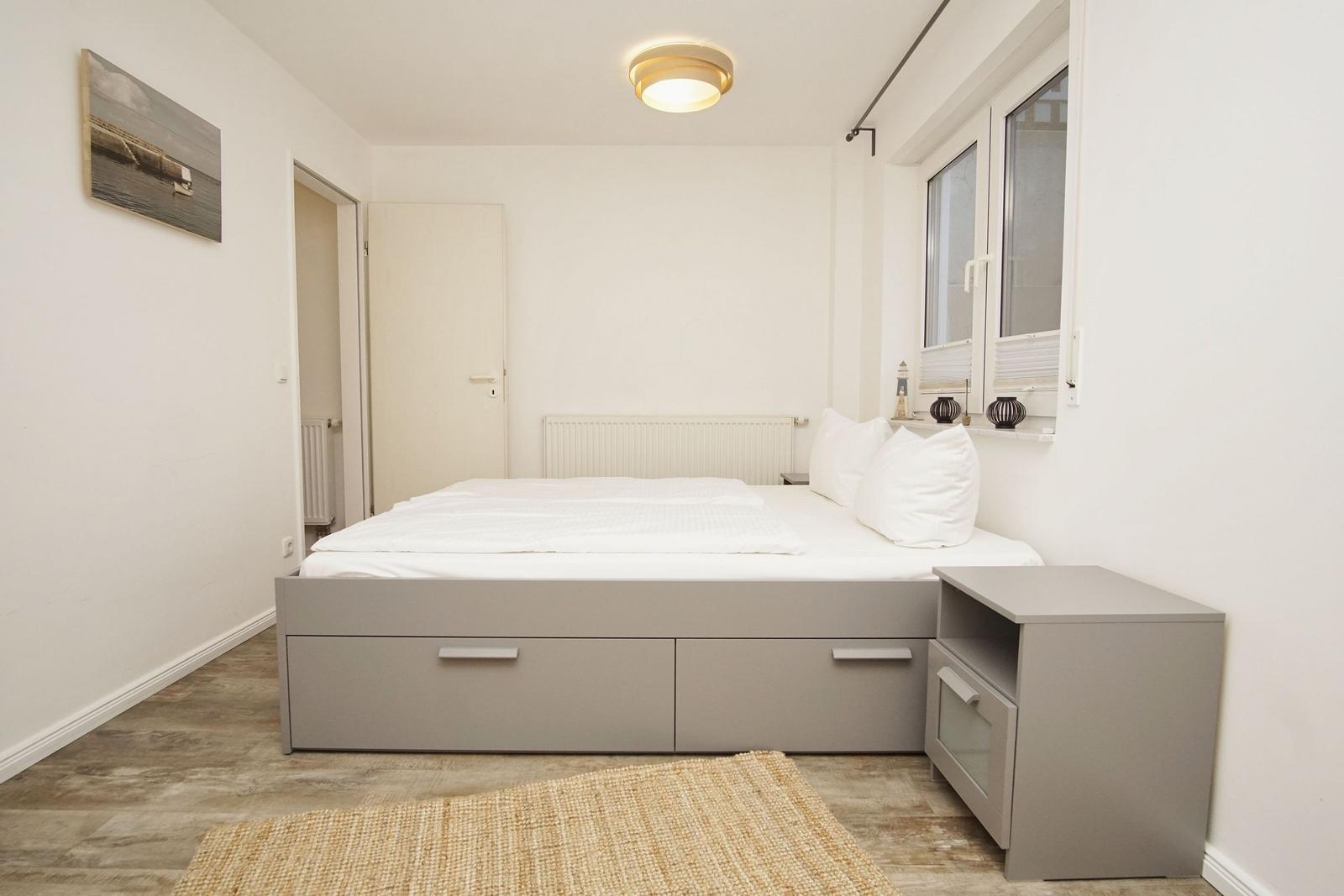 Schlafzimmer mit Bett, Nachttisch und Fenster