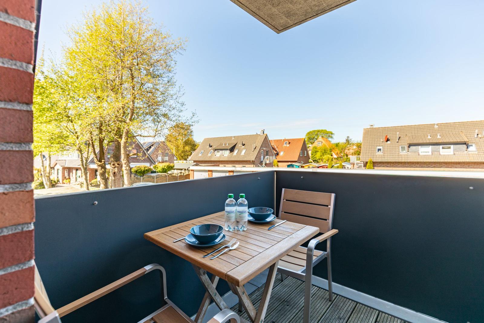 Terrace with table, chairs, and view of houses and trees.