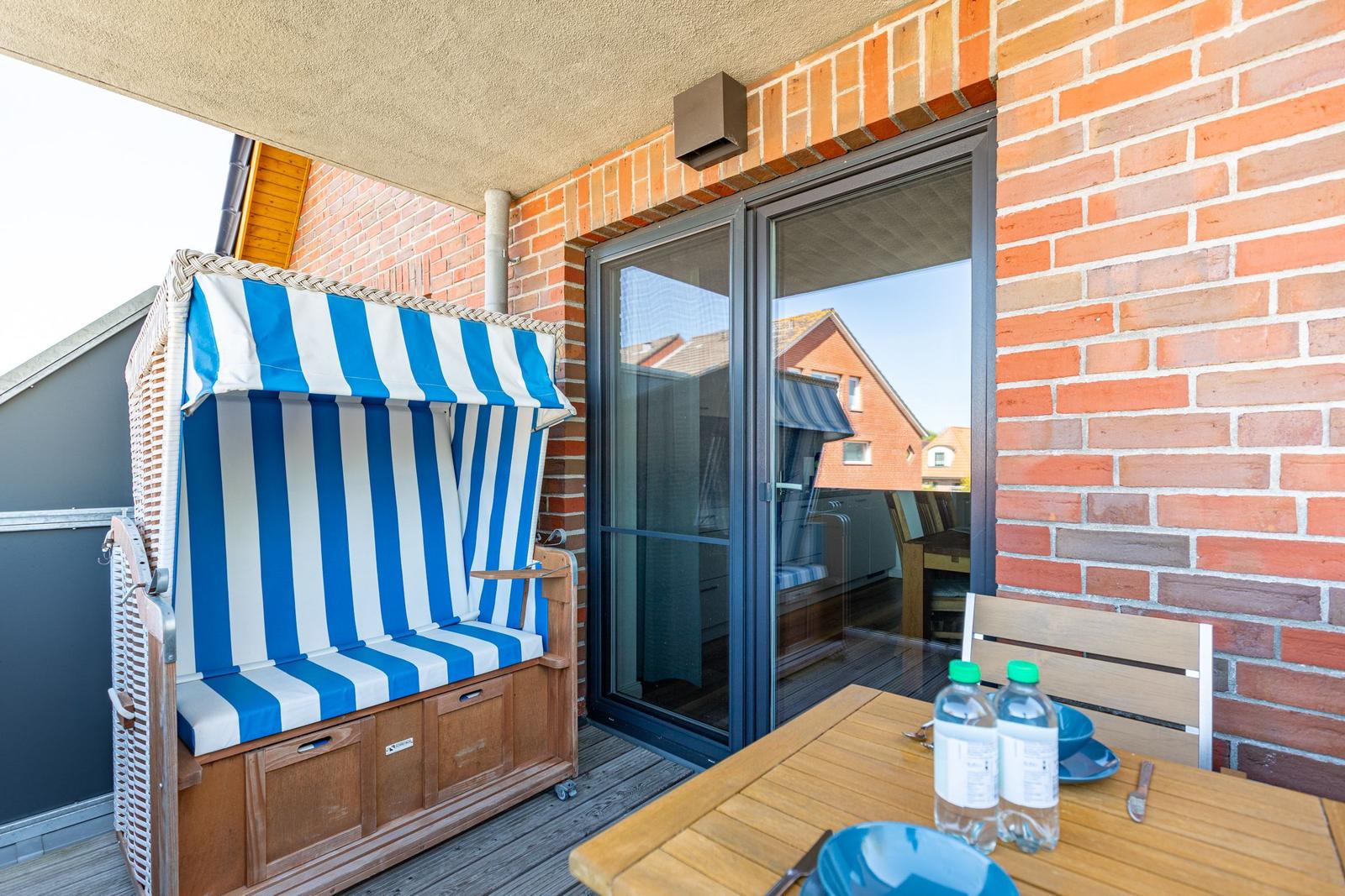 Terrace with beach chair, table, and chairs. Glass door leads into the house.