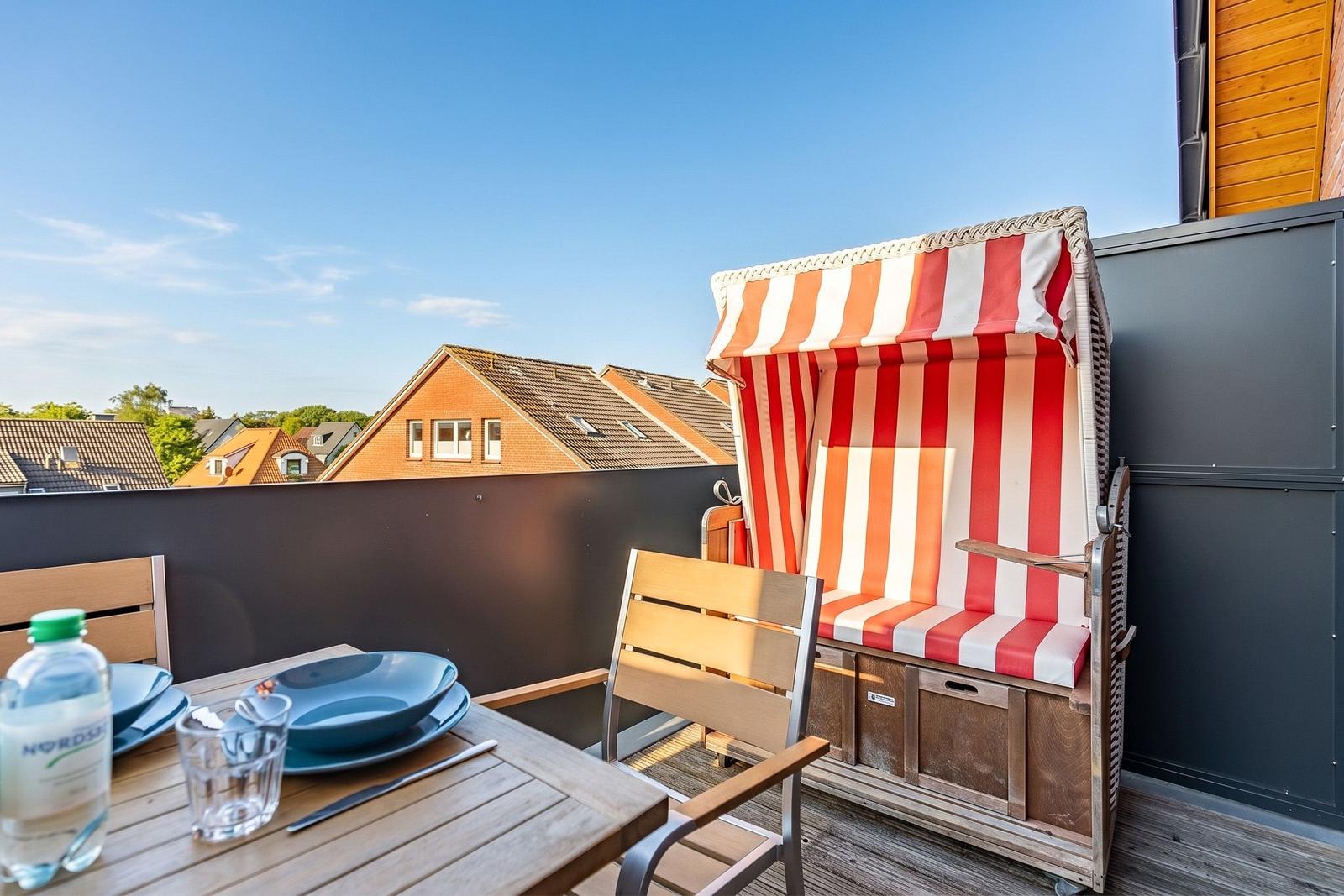 Terrace with beach chair, table and chairs. View of rooftops and sky.