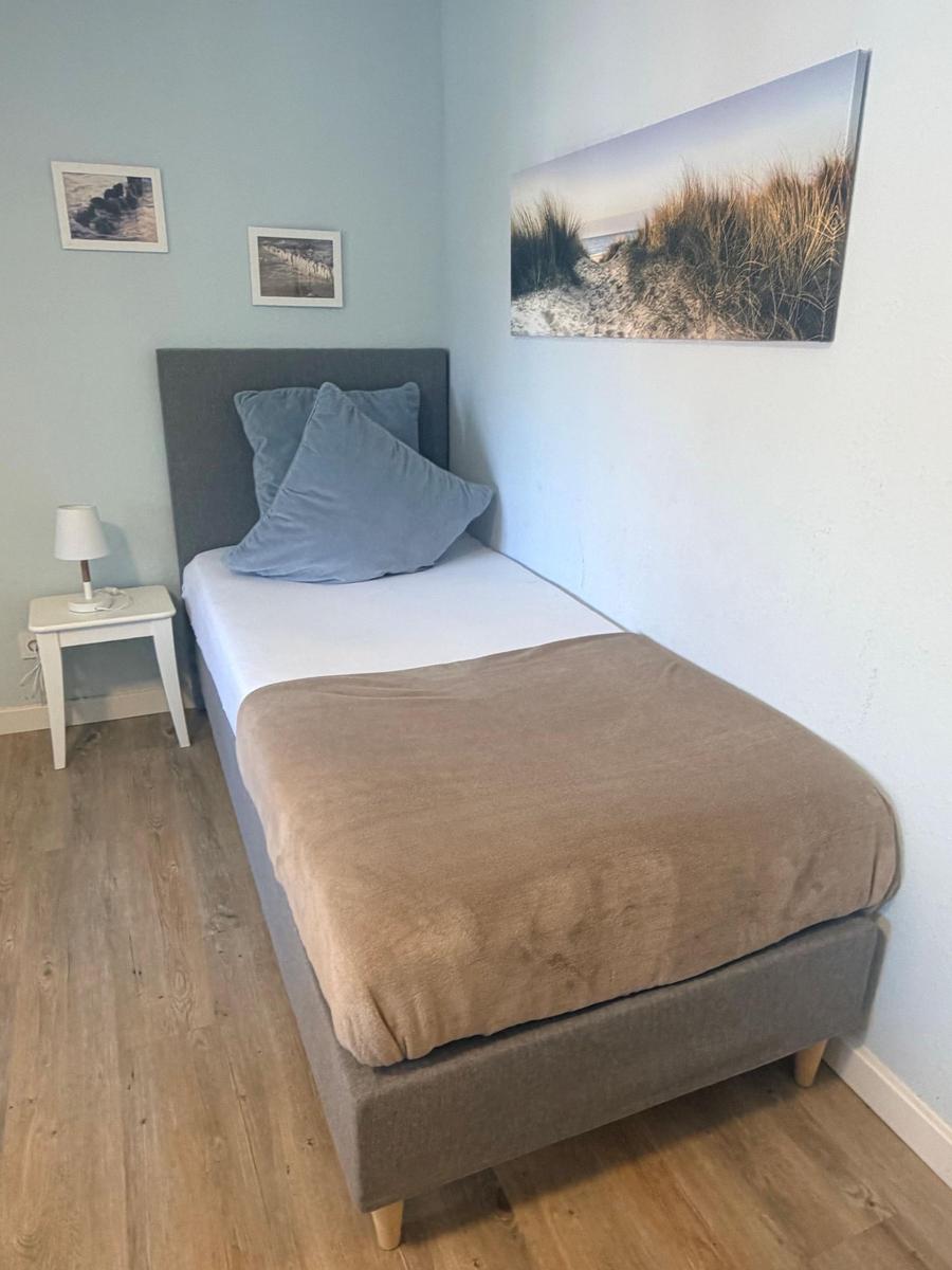 Ein Schlafzimmer mit einem Bett, einer Nachttischlampe und Wandbildern.