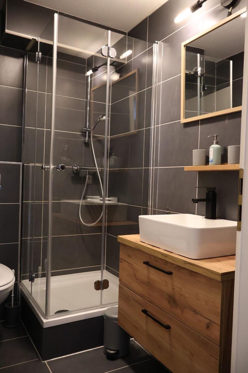 Dusche mit Glaswand, Waschbecken auf Holzunterschrank und Spiegel