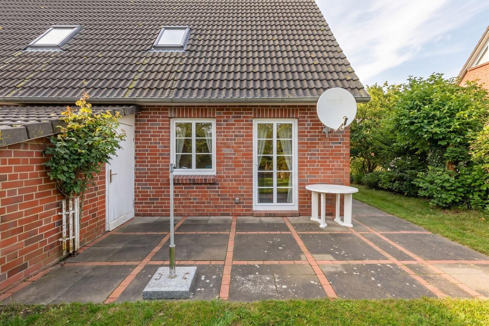 Rotes Backsteingebäude mit Dachfenstern, Terrasse und Satellitenschüssel.