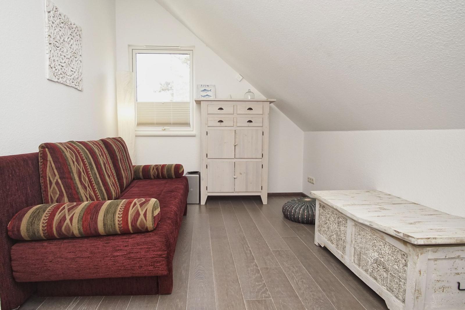 Ein Raum mit einem roten Sofa, einem weißen Schrank und einem weißen Tisch.