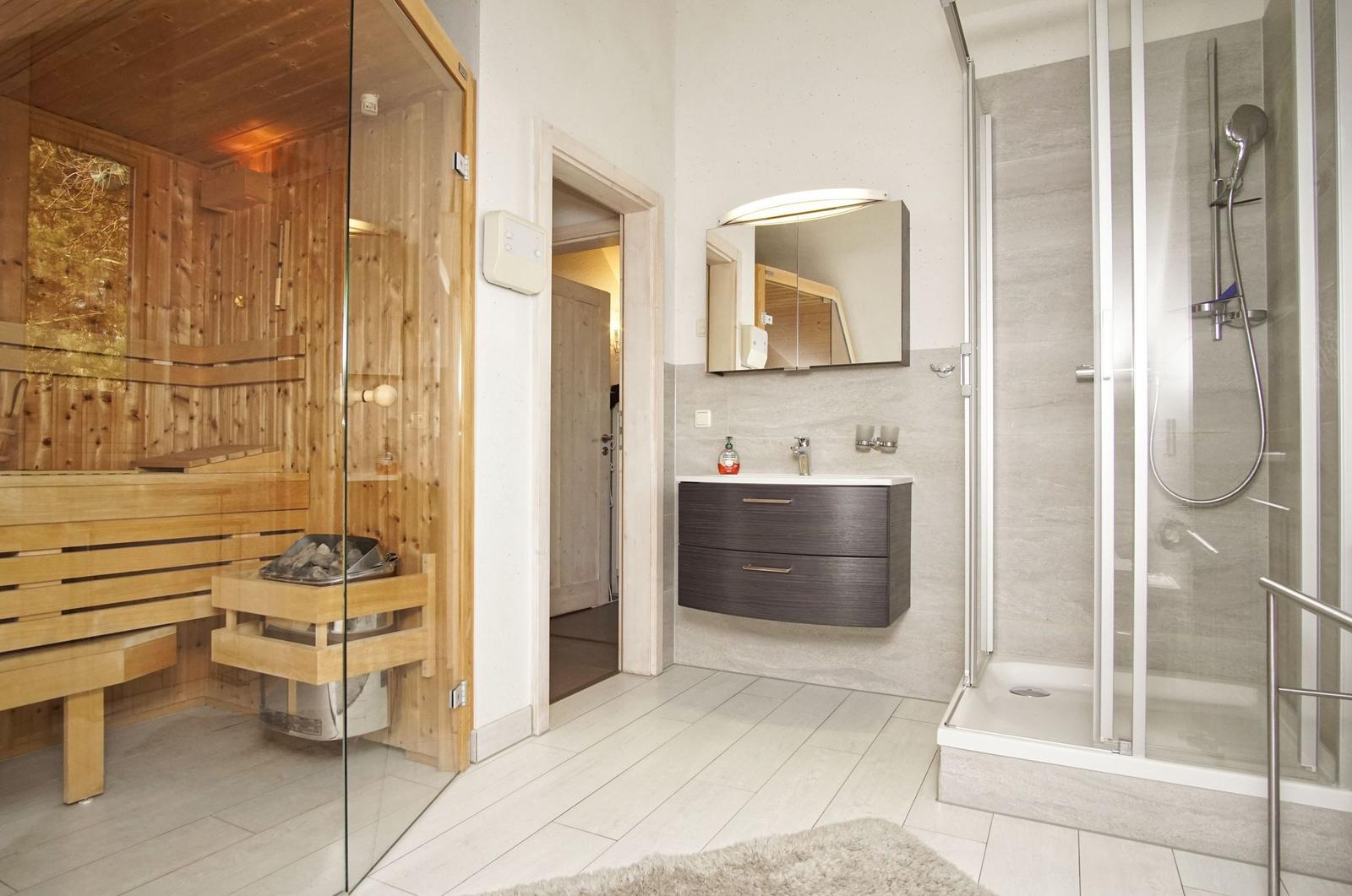 Bad mit Dusche, Waschbecken und Sauna mit Holzbank.