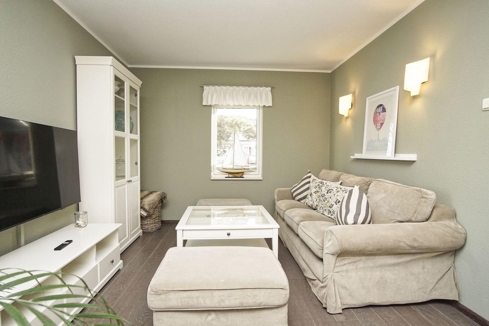 Wohnzimmer mit Sofa, Couchtisch und Fernseher an der Wand.