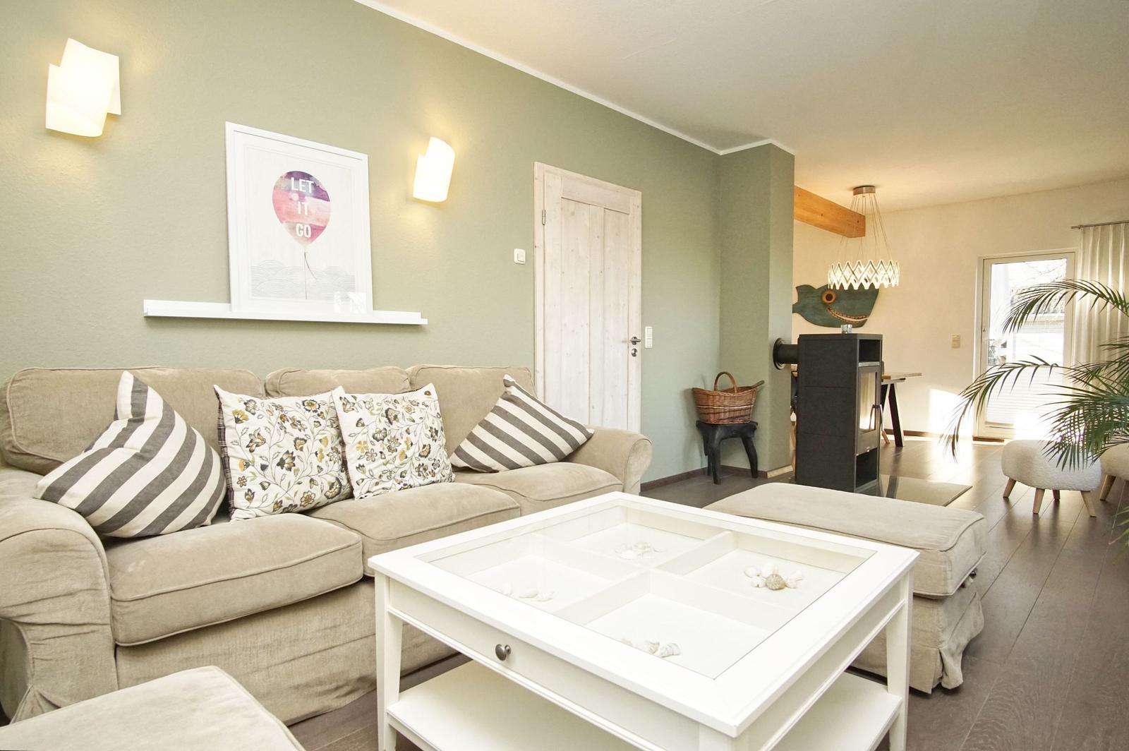Wohnzimmer mit Sofa, Couchtisch und Wandbild. Im Hintergrund ist ein Kamin zu sehen.