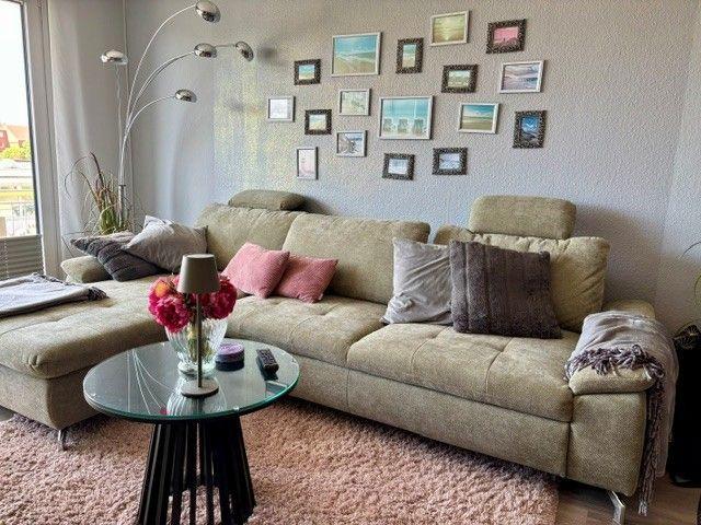 Ein Wohnzimmer mit einem großen Sofa, einer Glasplatte und einer Wand mit Bildern.