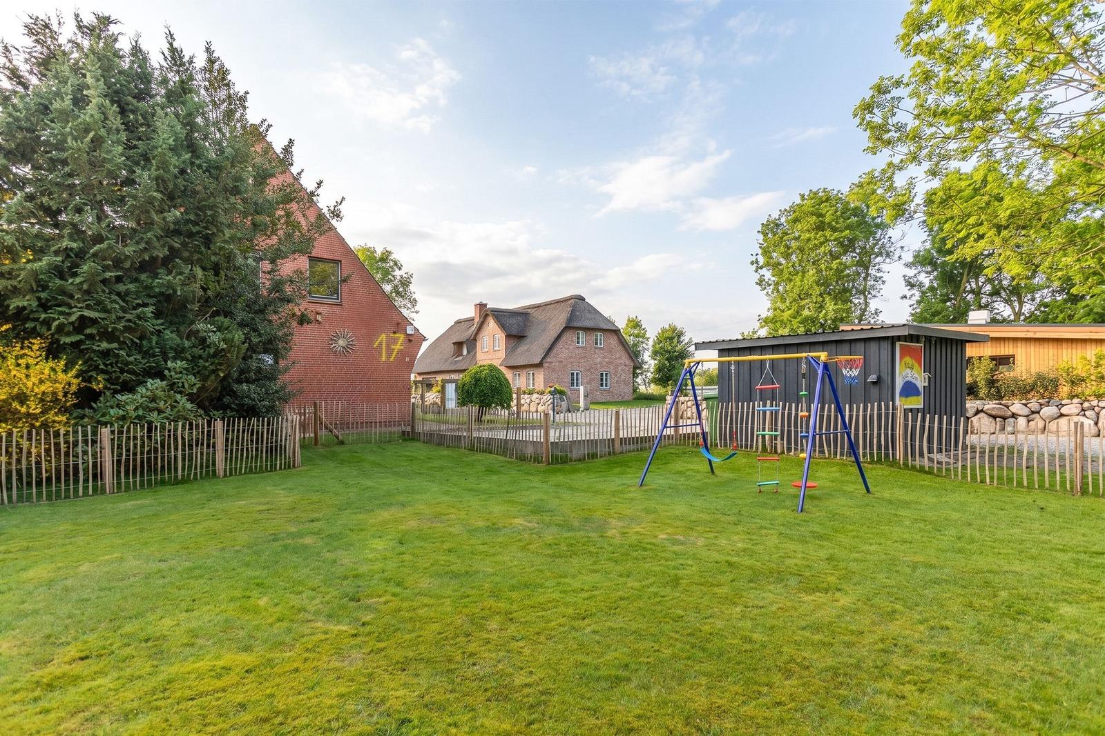 Grüner Garten mit Spielplatz und mehreren Häusern im Hintergrund.