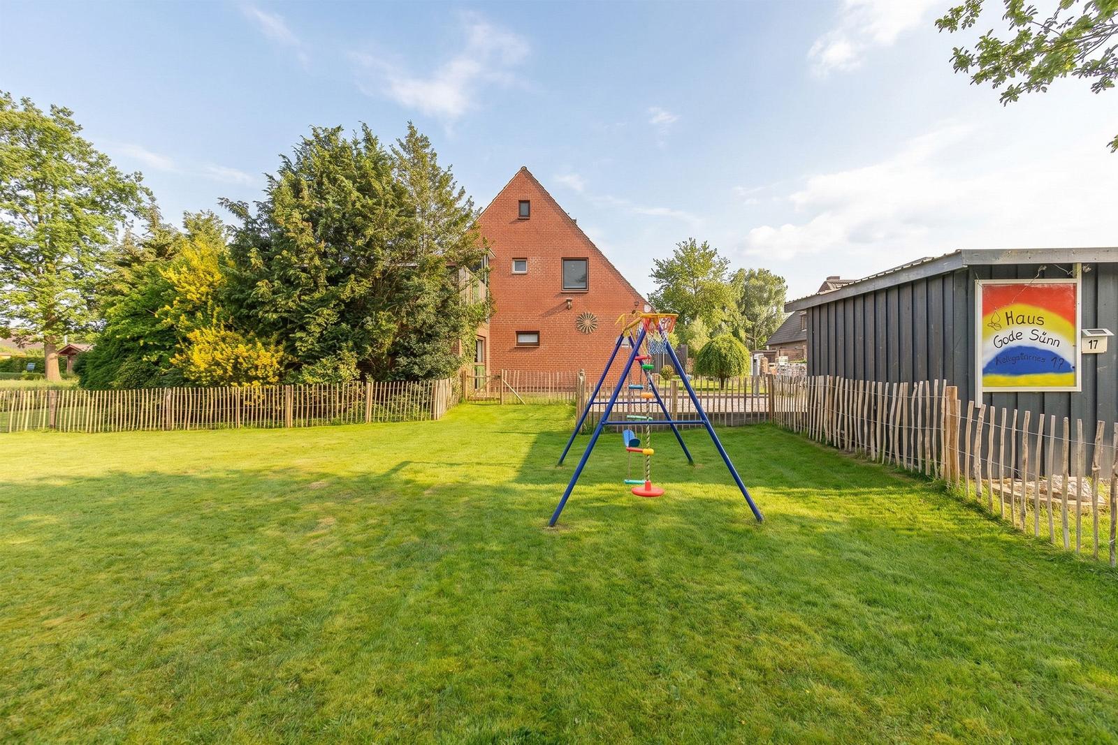Rotes Haus mit Spielplatz und Grünfläche im Hintergrund.