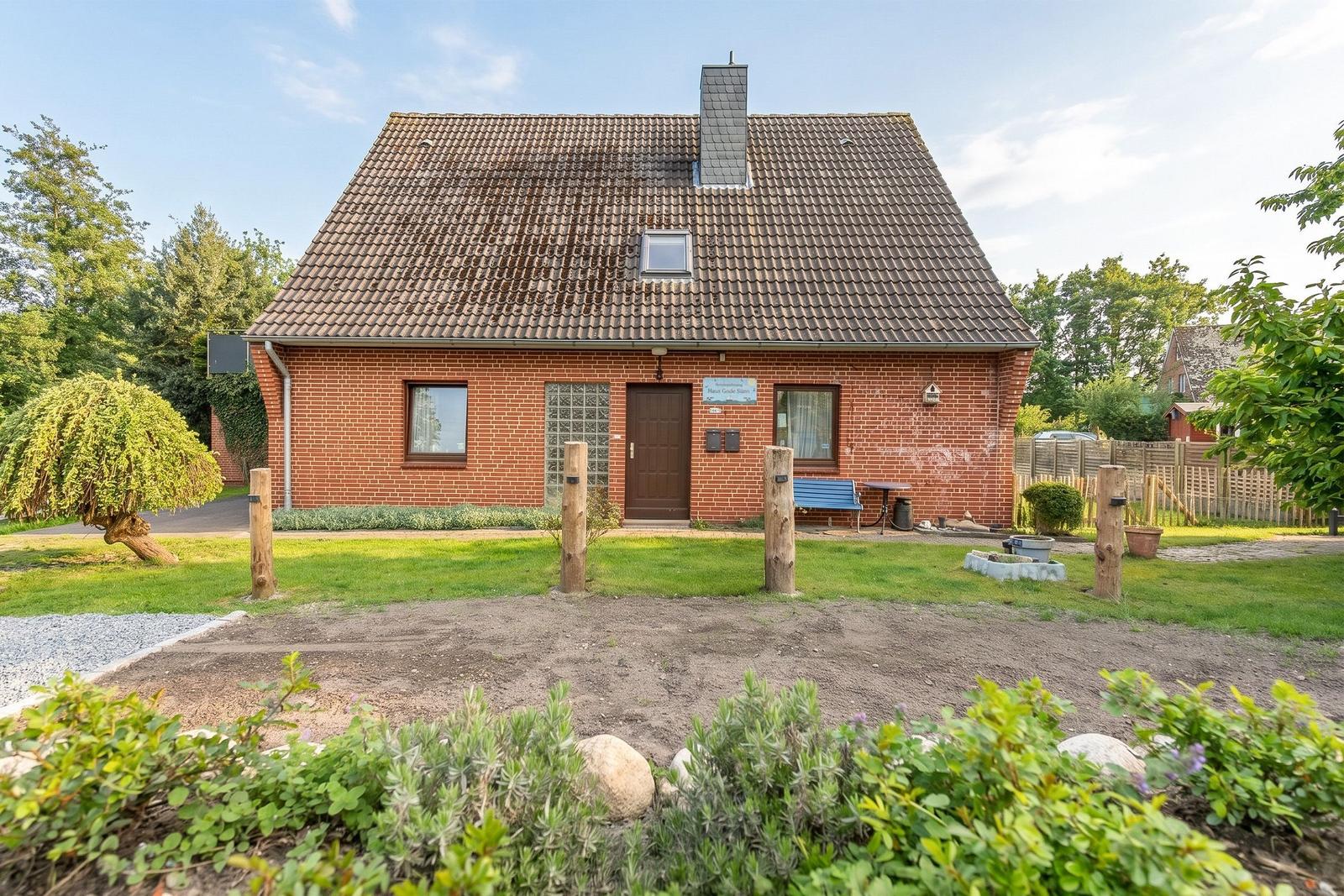 Ein rotes Backsteingebäude mit Dach und Garten.