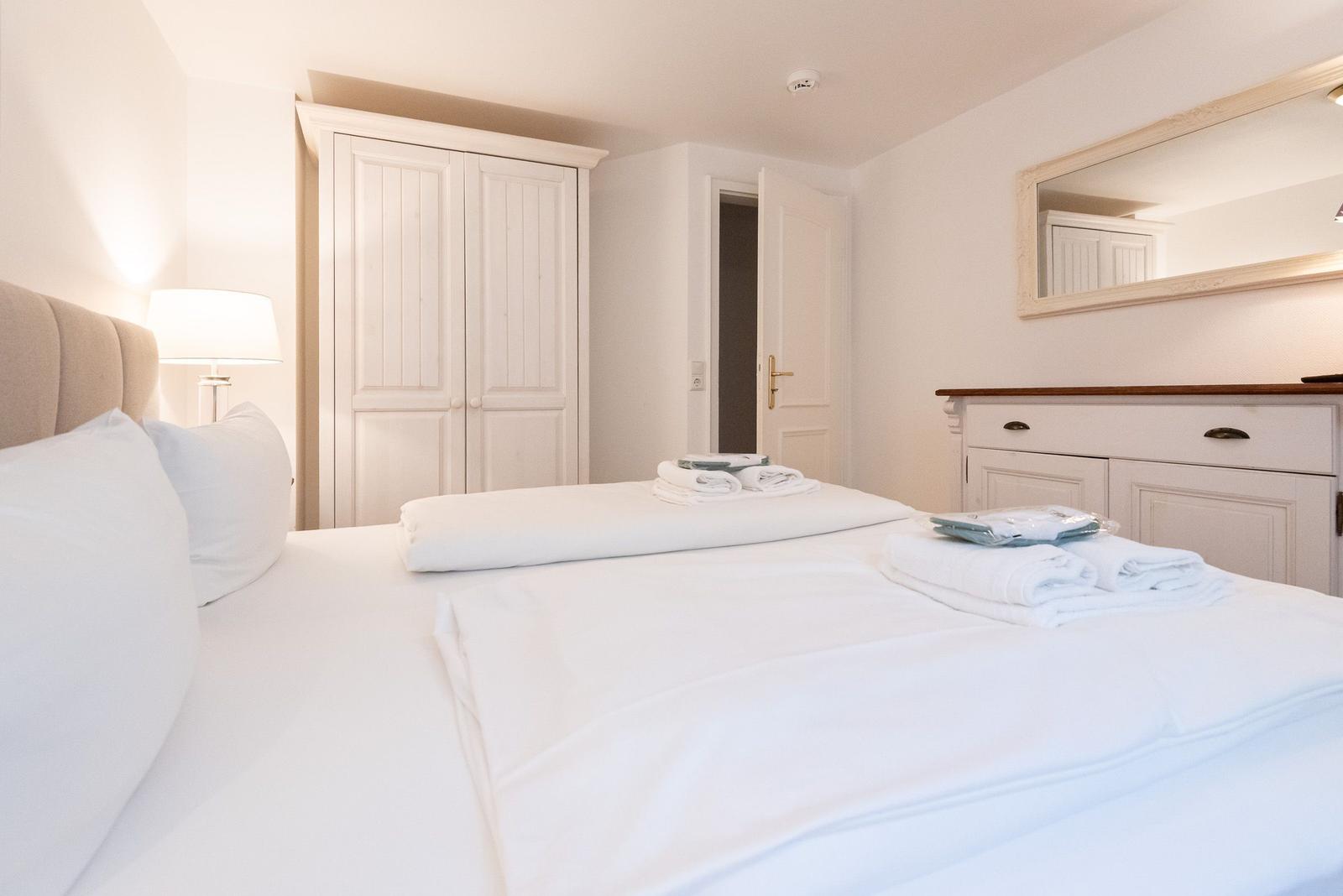 Bedroom with bed, wardrobe, and mirror cabinet. Towels and bedding are ready.