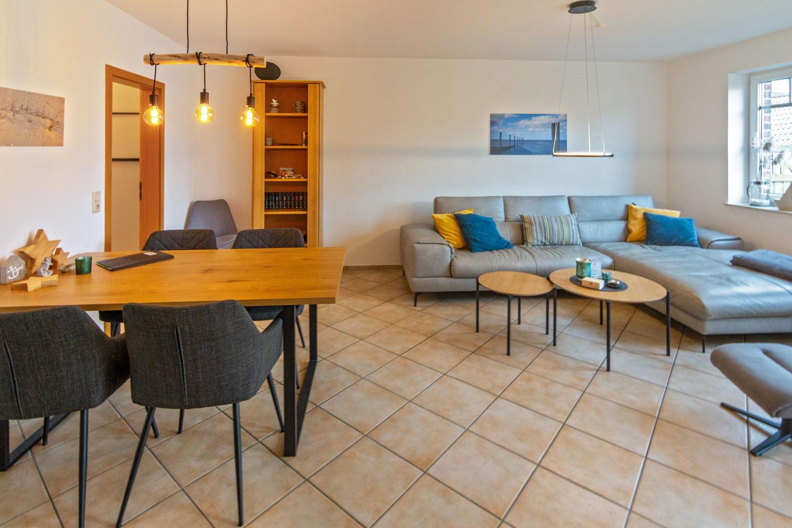 Wohn- und Essbereich mit Sofa, Tisch und Stühlen sowie Wandbild.