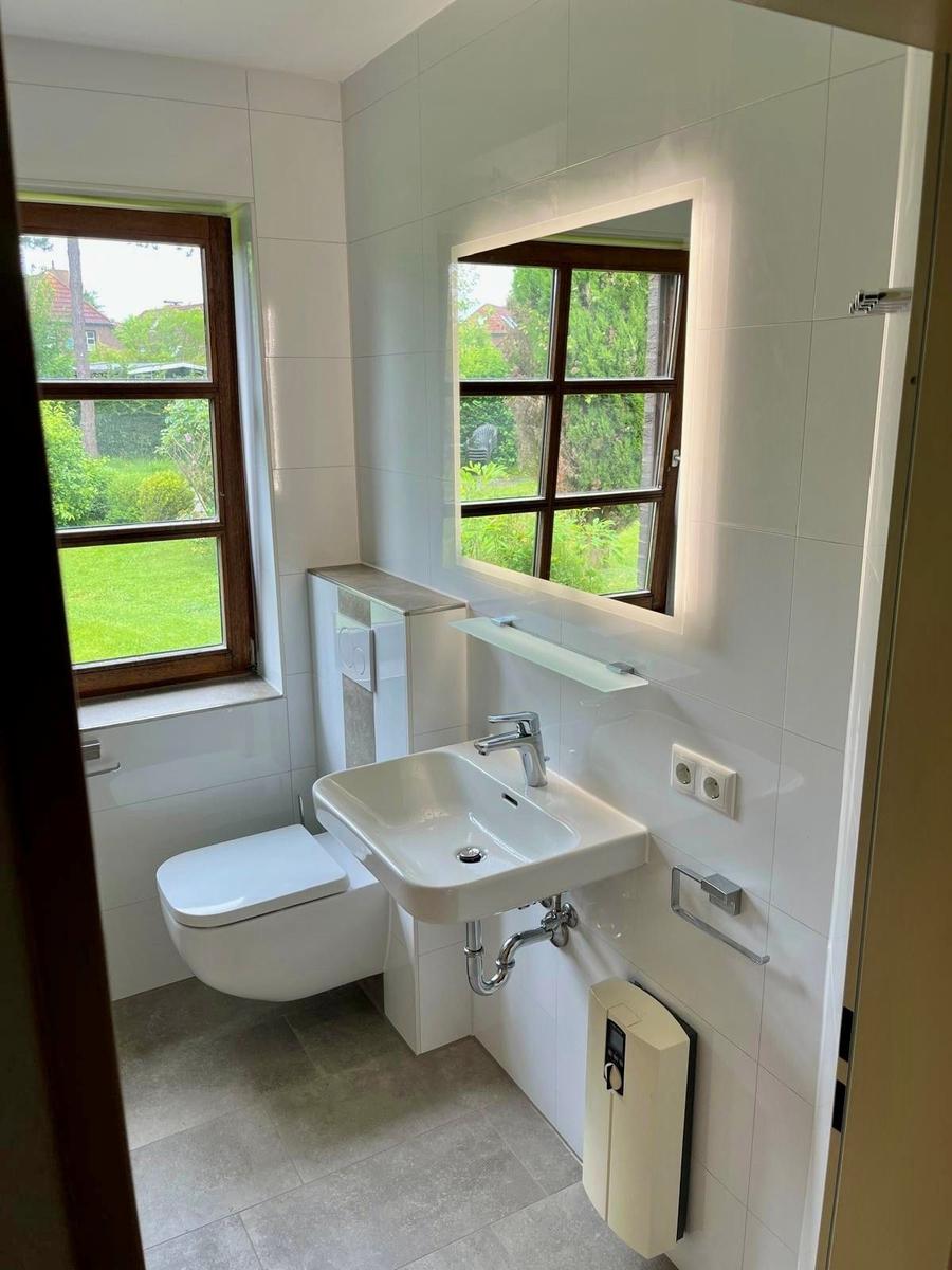 Badezimmer mit Toilette, Waschbecken und Fenster mit Blick auf Garten.