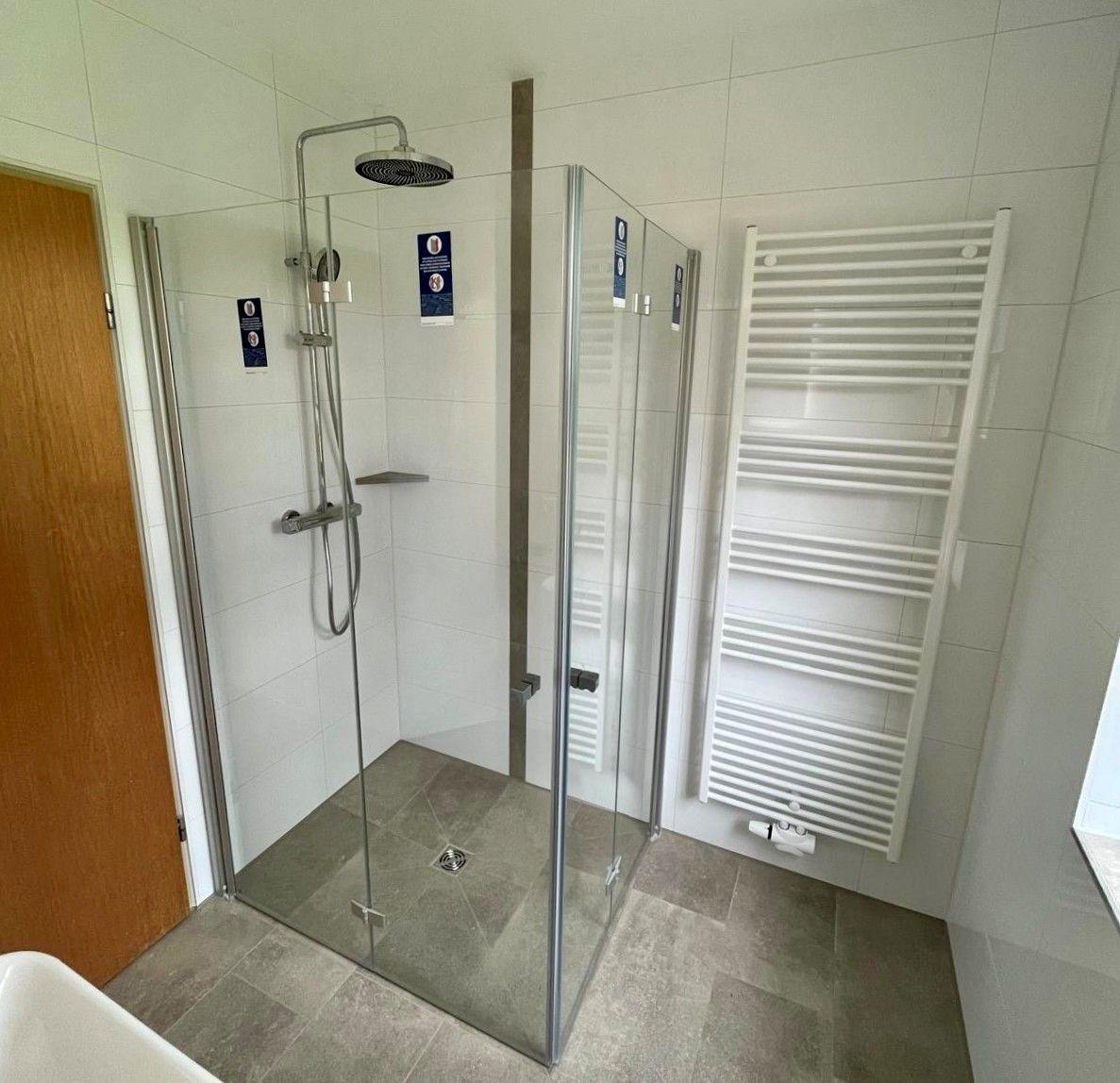 Dusche mit Glaswand, Heizkörper und Duschbrause