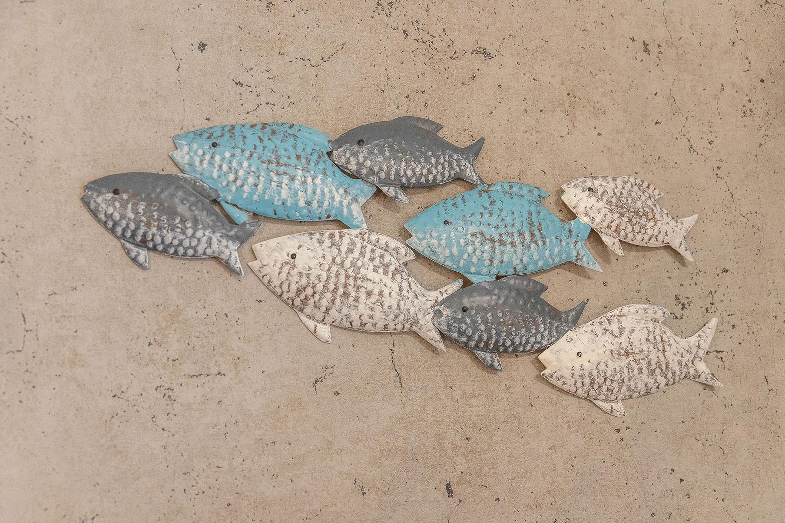 Sieben metallene Fische in Blau und Weiß an einer Wand