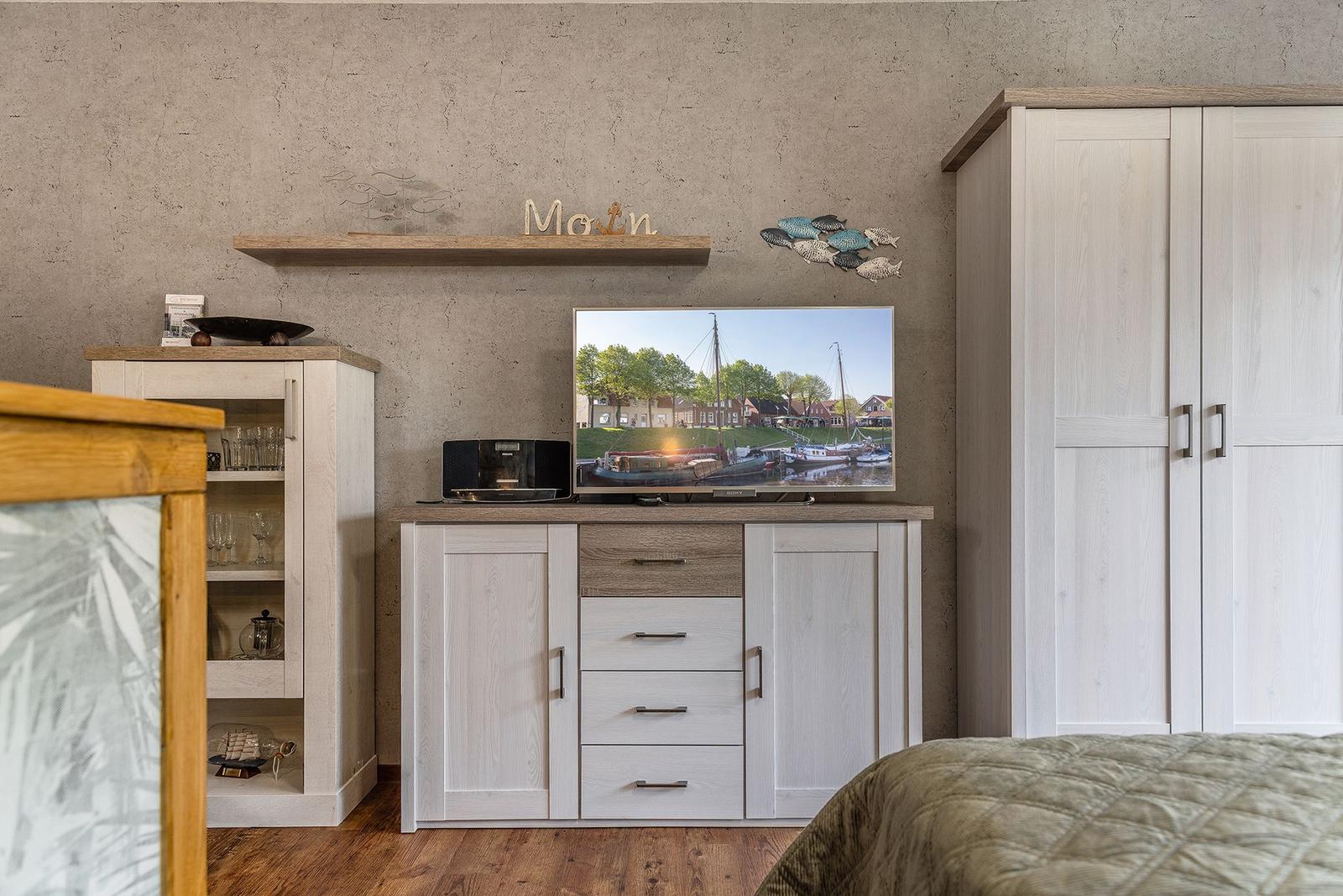 Schlafzimmer mit TV, Kleiderschrank und Sideboard. Wanddekoration und Holzmöbel.