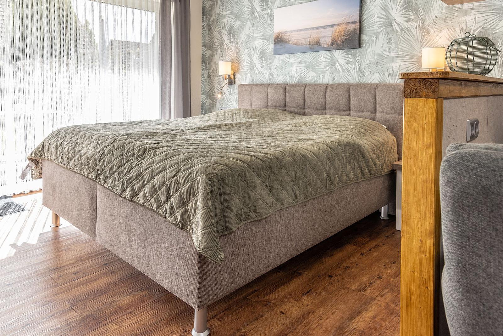 Schlafzimmer mit Bett, Holzboden und Wandbild
