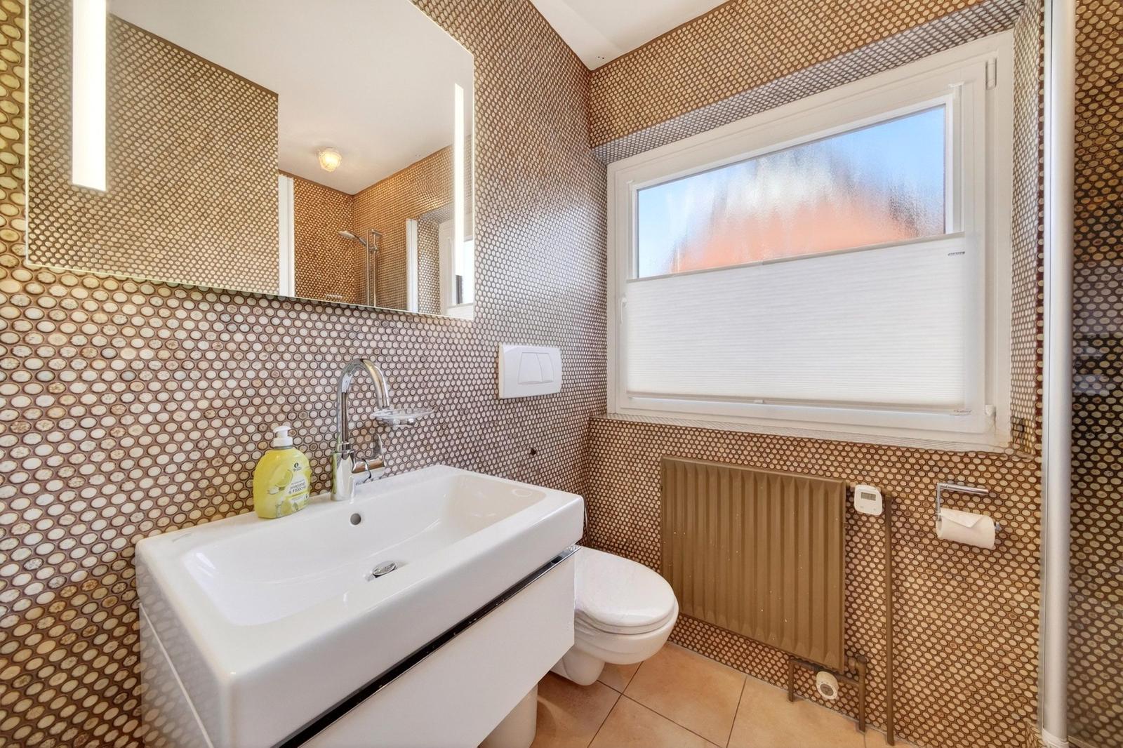 Badezimmer mit Waschbecken, Toilette und Spiegel an der Wand.