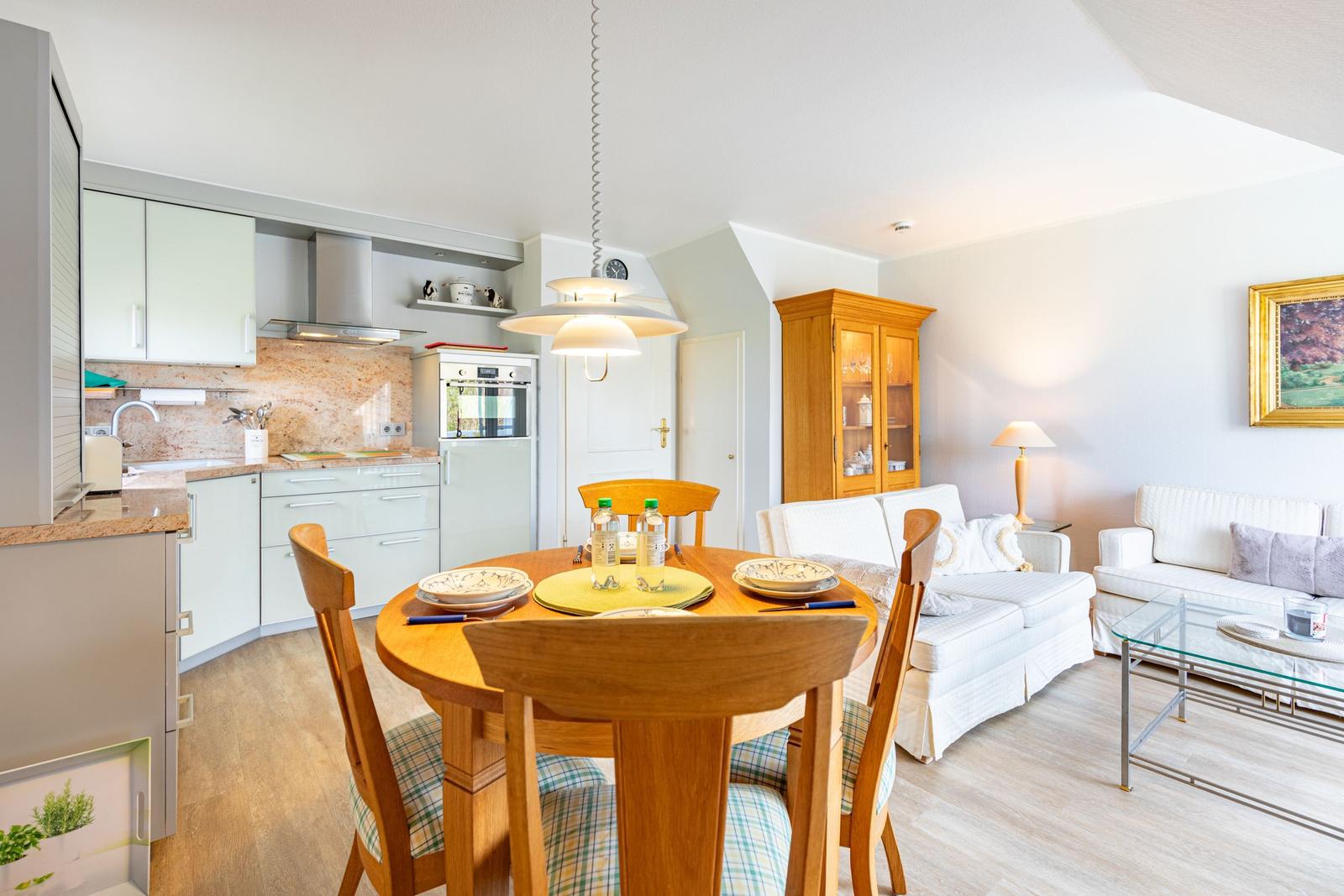 Kitchen with dining table, living room with sofa and glass table.