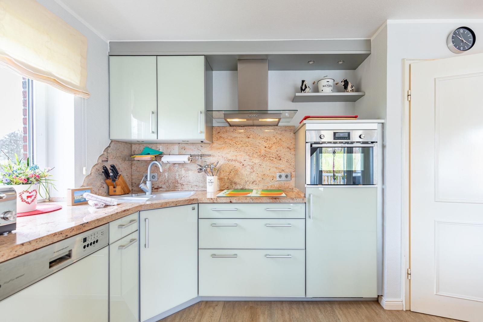 Kitchen with light cabinets, stone countertop, and built-in oven.