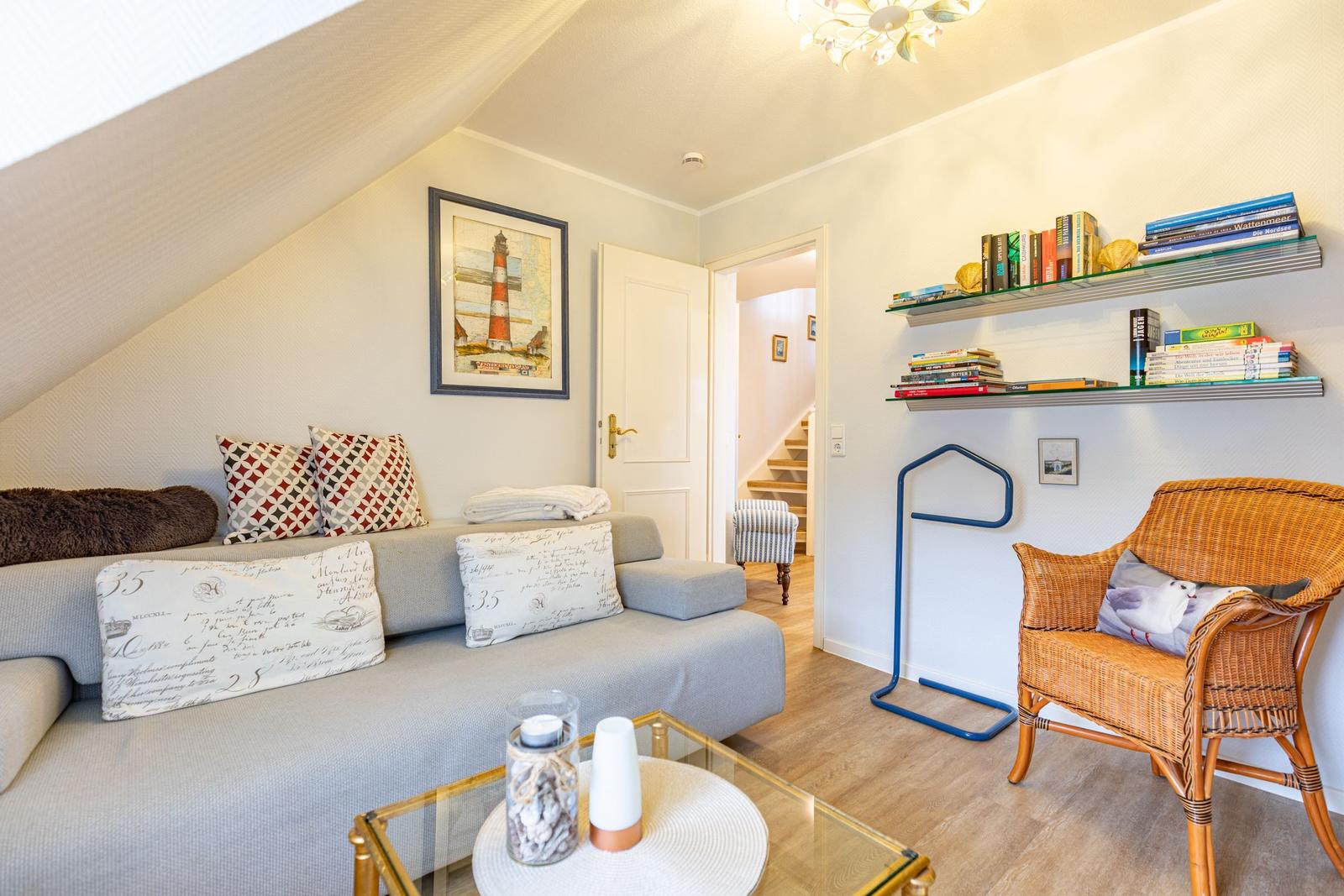 Living room with sofa, chair, and bookshelf on the wall.