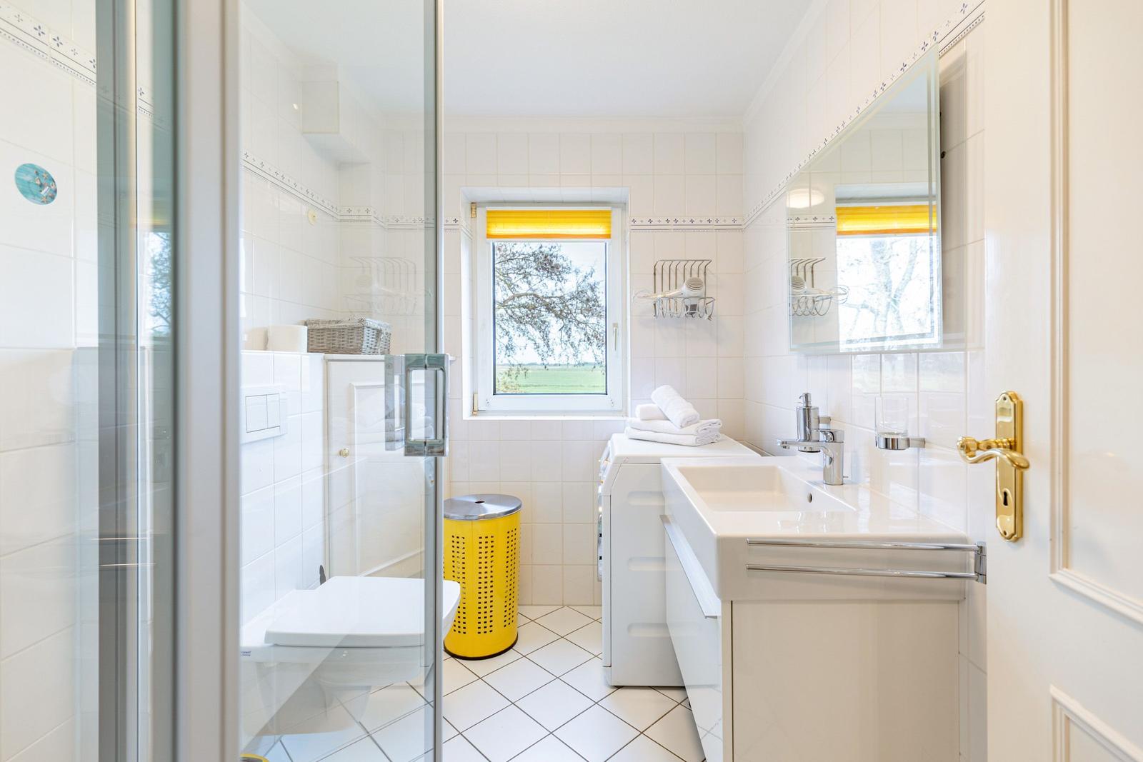 Bathroom with shower, sink, and window to the garden.