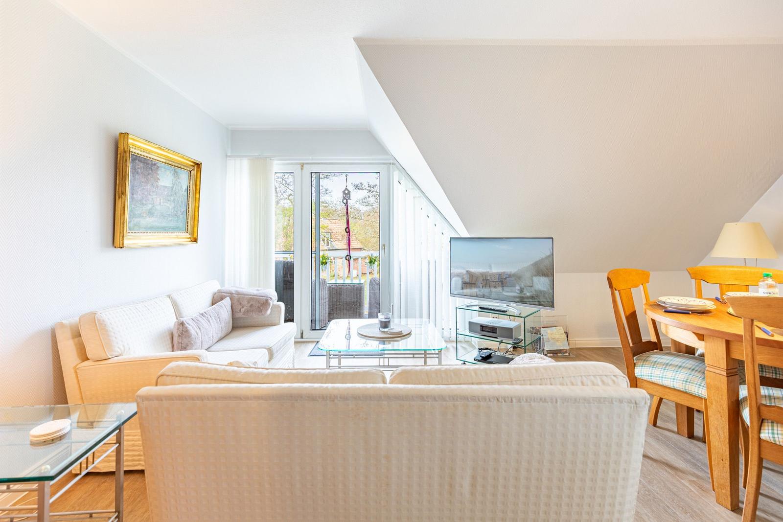 Living room with sofa, TV, and dining area. Terrace with garden view.
