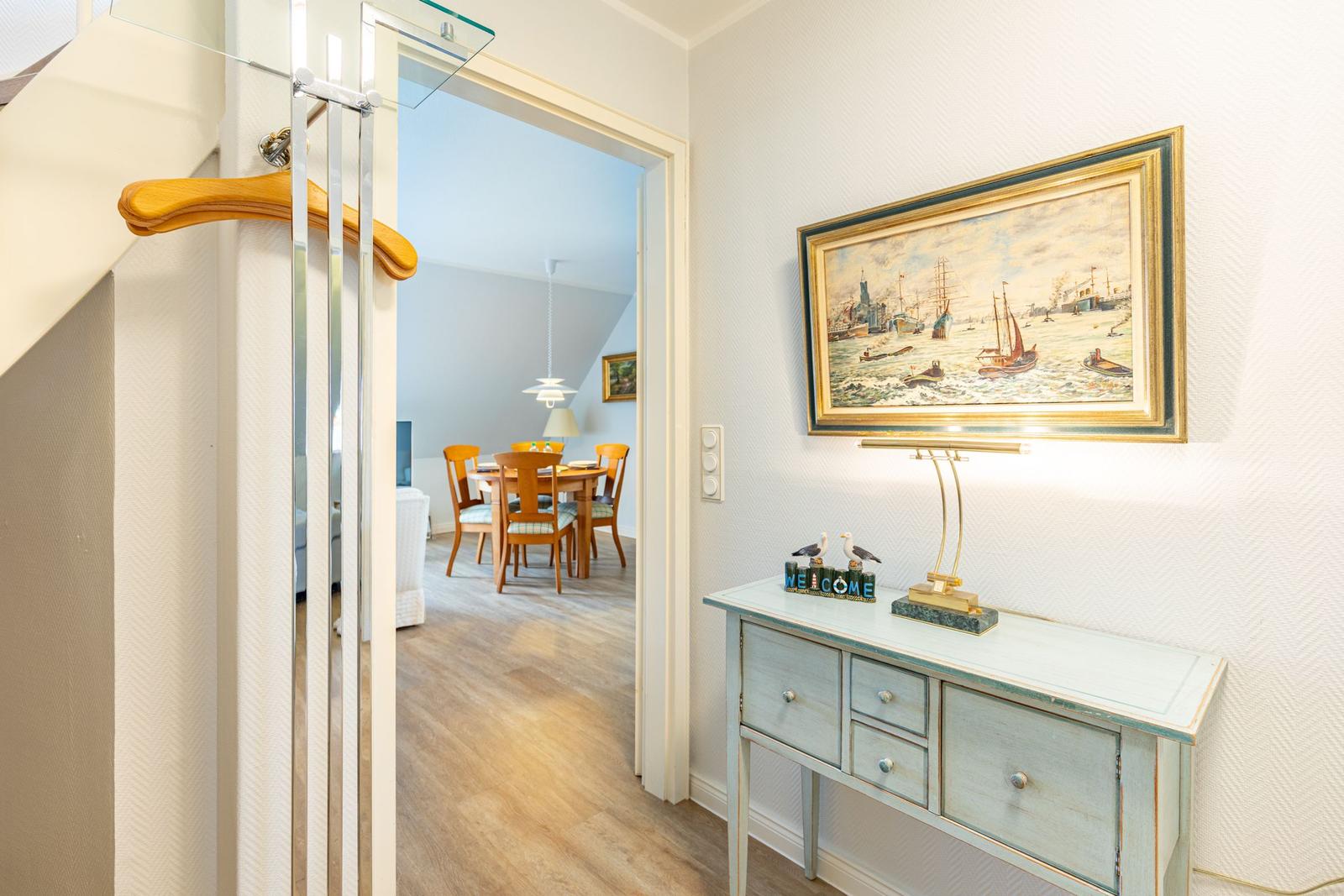 Entrance area with console table, painting, and view into dining room.