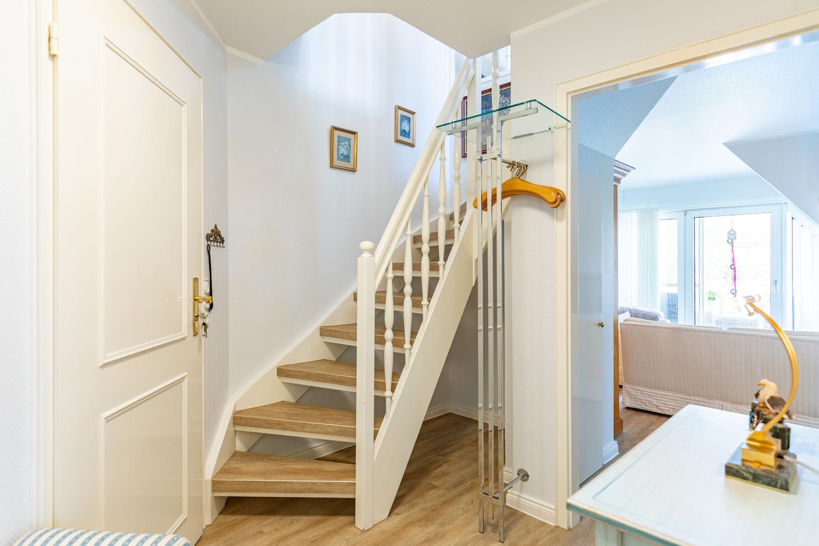House with staircase, glass railing, and adjacent rooms.
