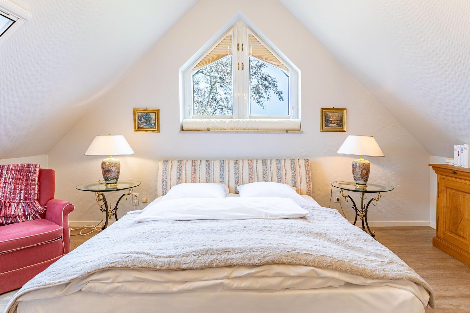 Bedroom with sloped ceiling, bed, window, and nightstands