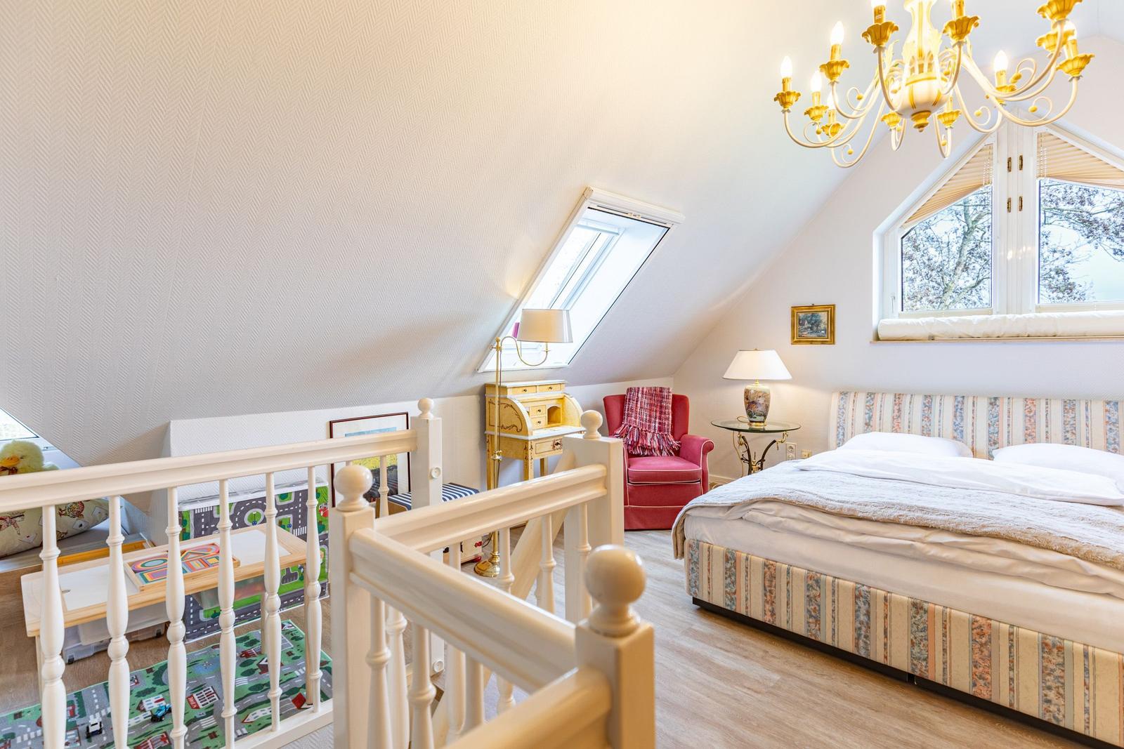 Bedroom with skylight, bed, armchair, and chandelier. Play area in foreground.