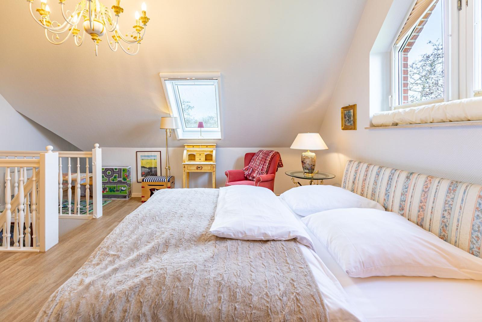 Bedroom with sloped ceiling, bed, armchair, and windows