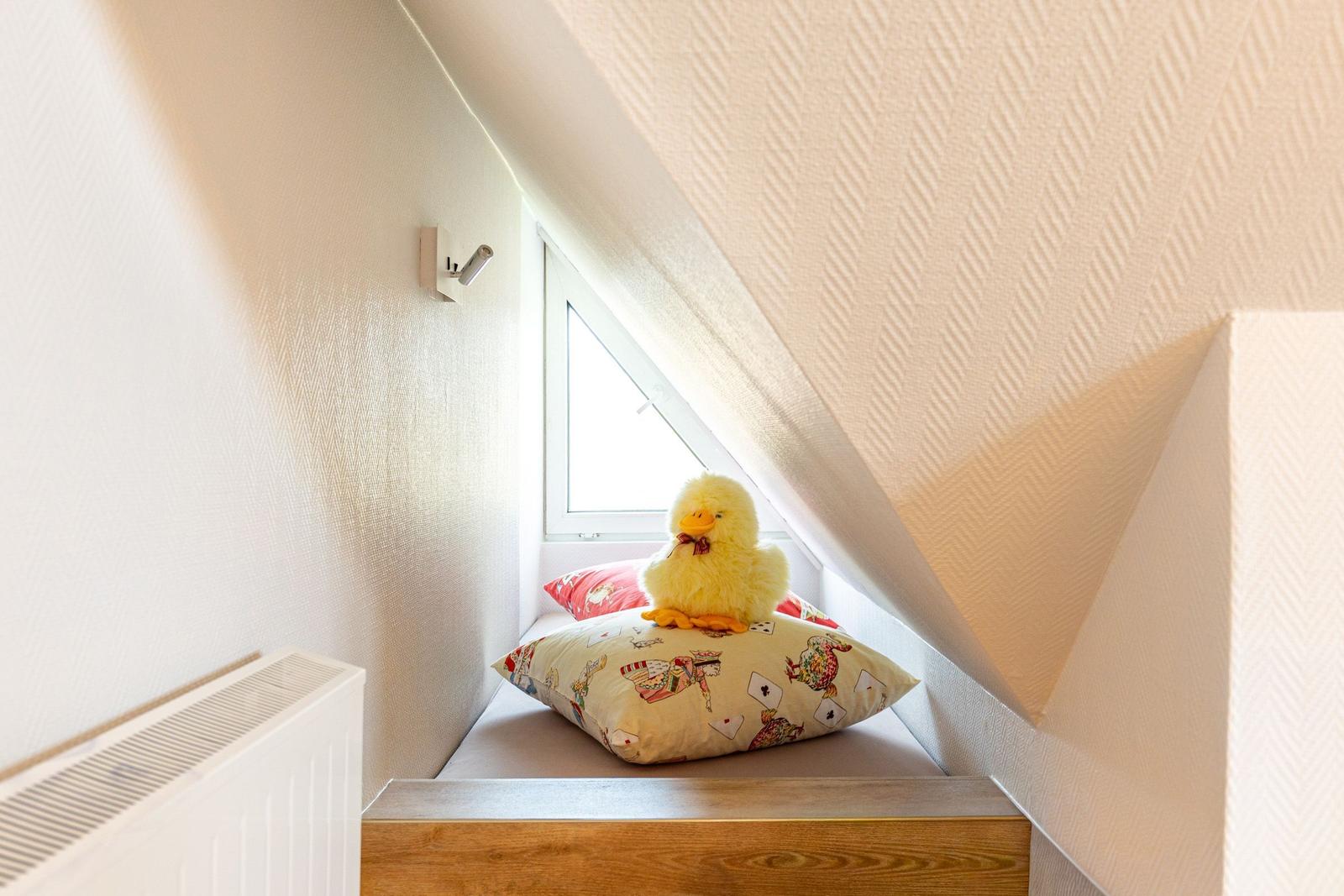 Attic corner with window, cushions, and plush duck.