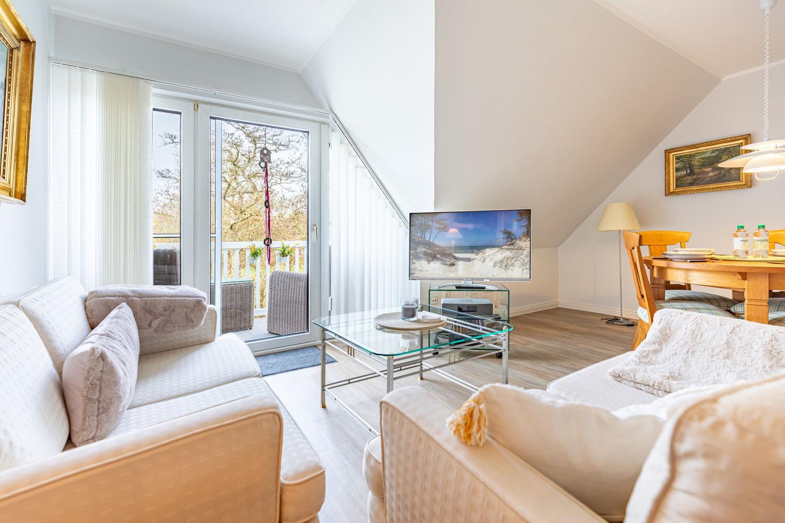 Living room with sofa, TV, and terrace. Dining area with wooden table.