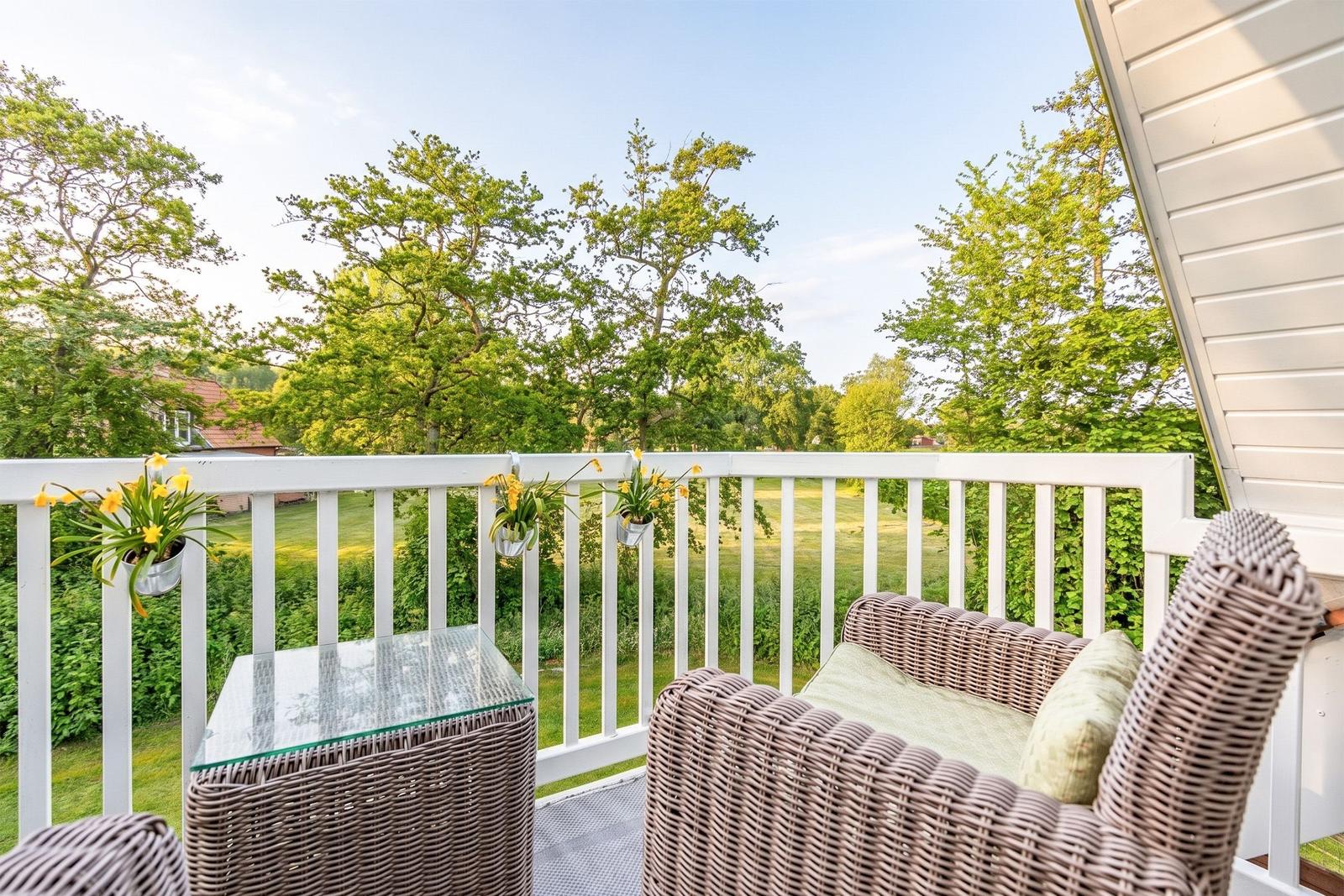 Terrace with wicker furniture and view of green trees.