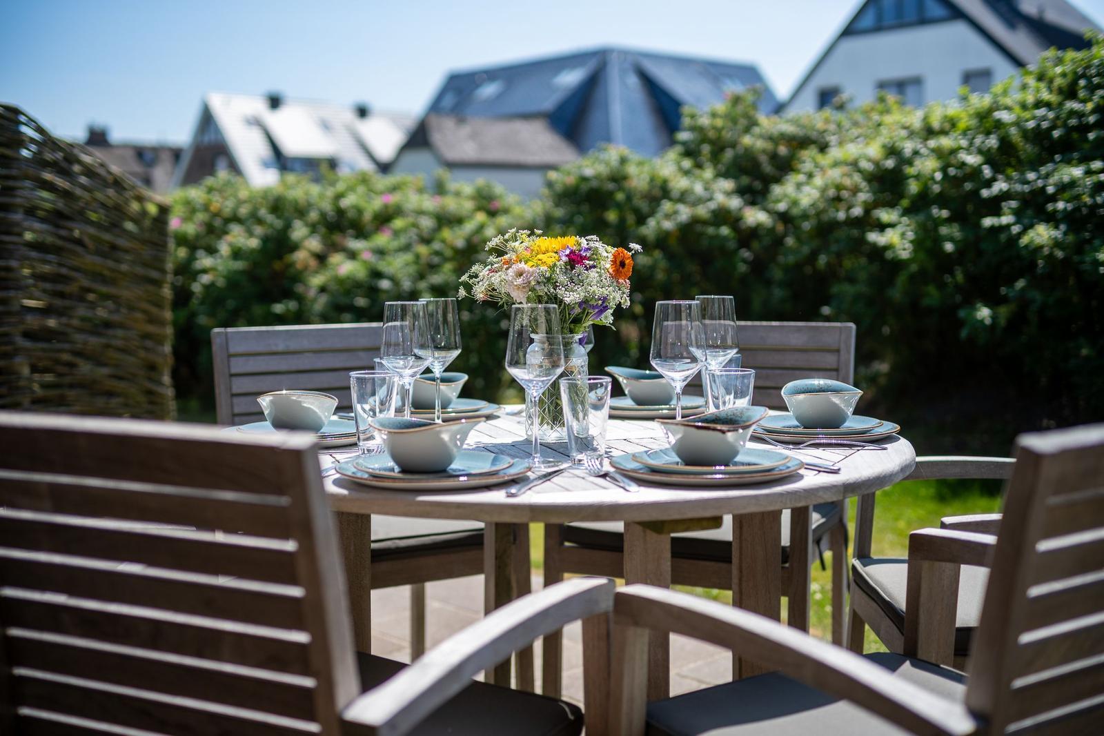Runder Tisch mit Stühlen und gedecktem Platz im Garten.