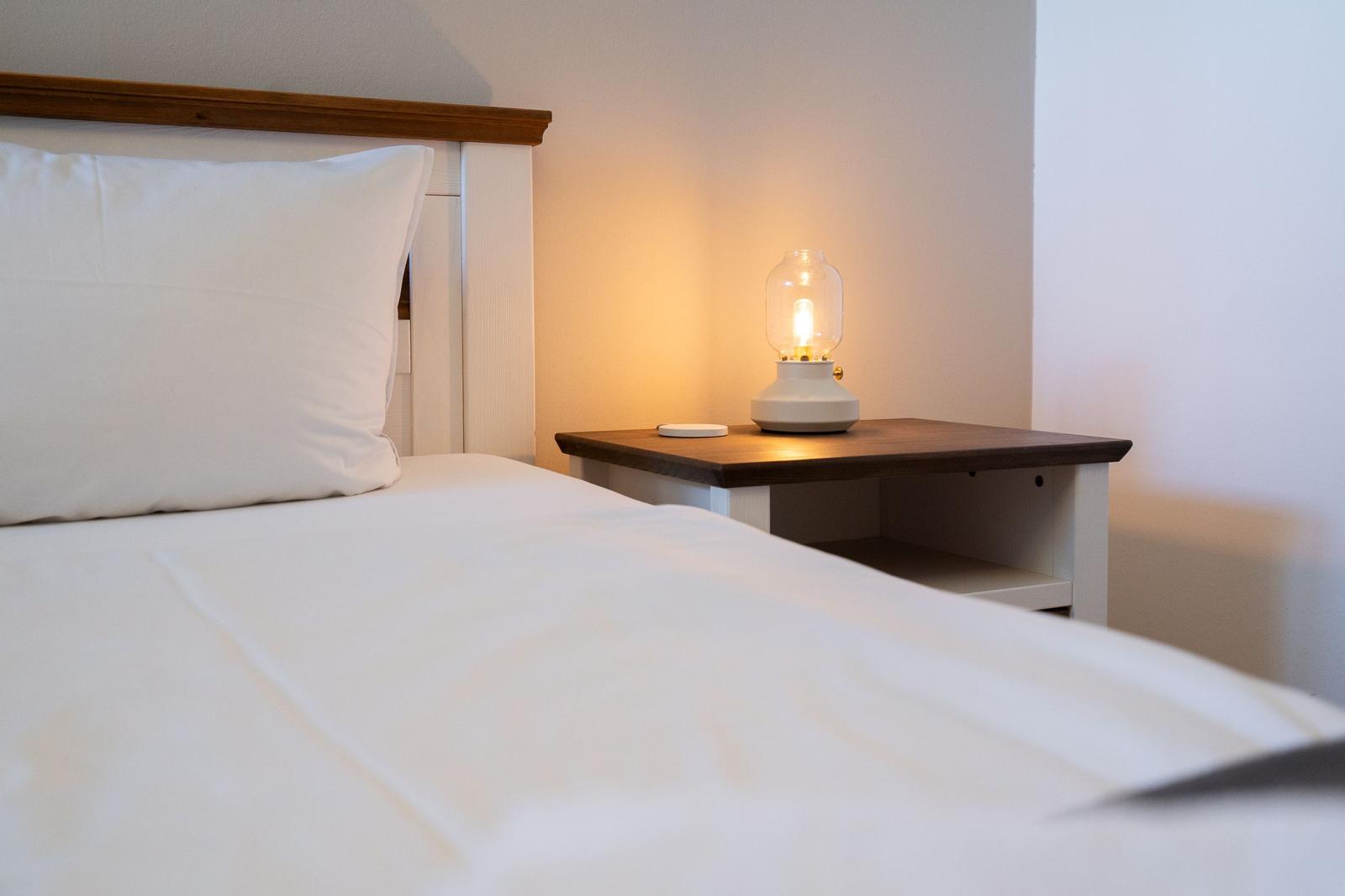 Ein Bett mit weißer Bettwäsche und einem Nachttisch mit einer Lampe.
