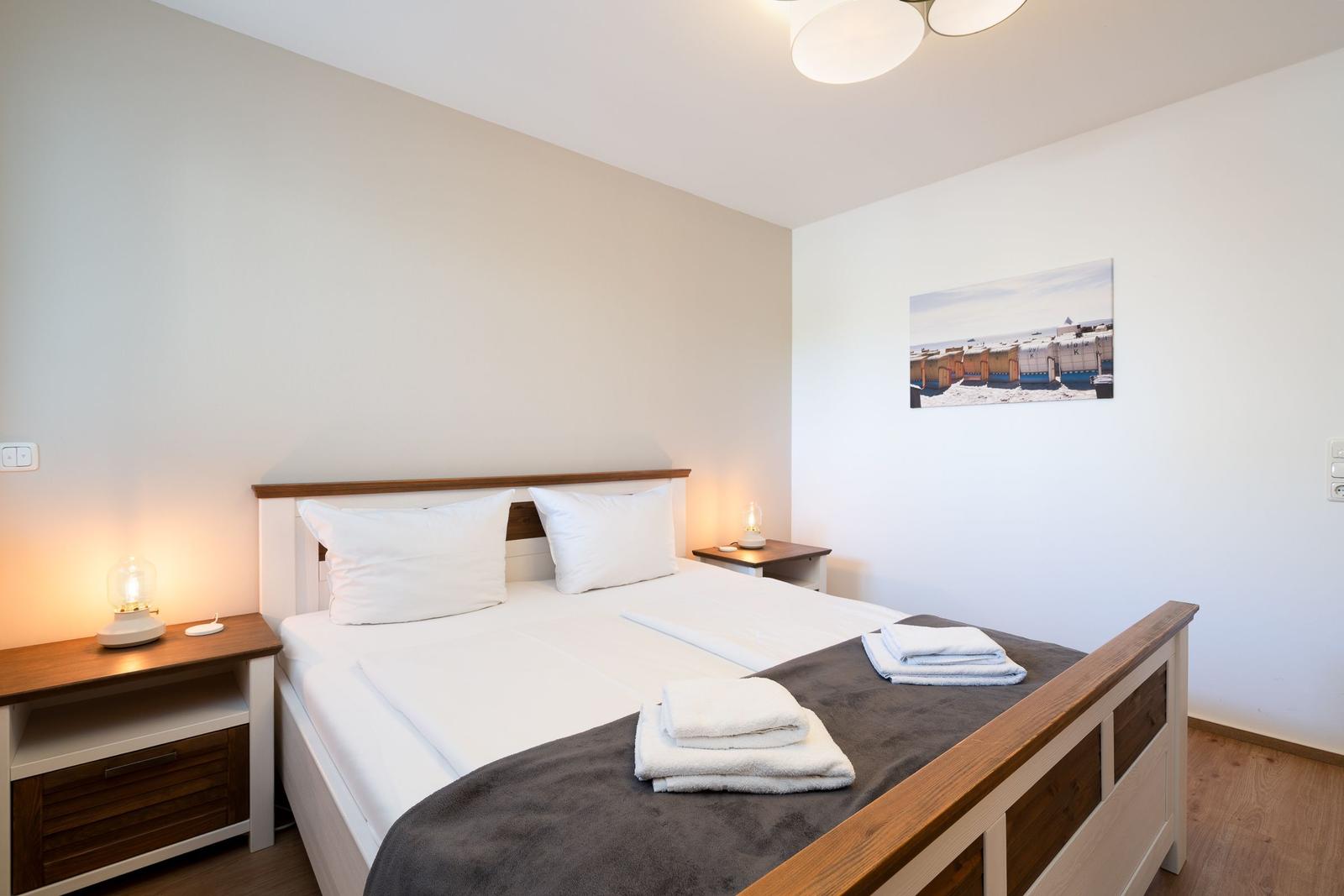 Schlafzimmer mit Bett, Nachttischen und Wandbild.