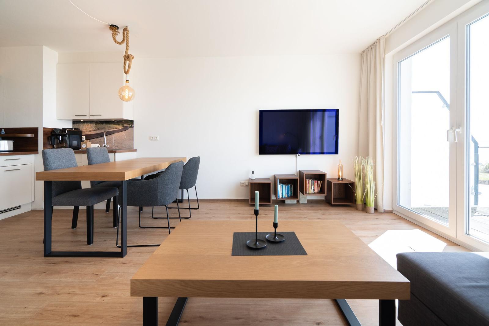 Wohn- und Essbereich mit TV, Esstisch und Holzboden.