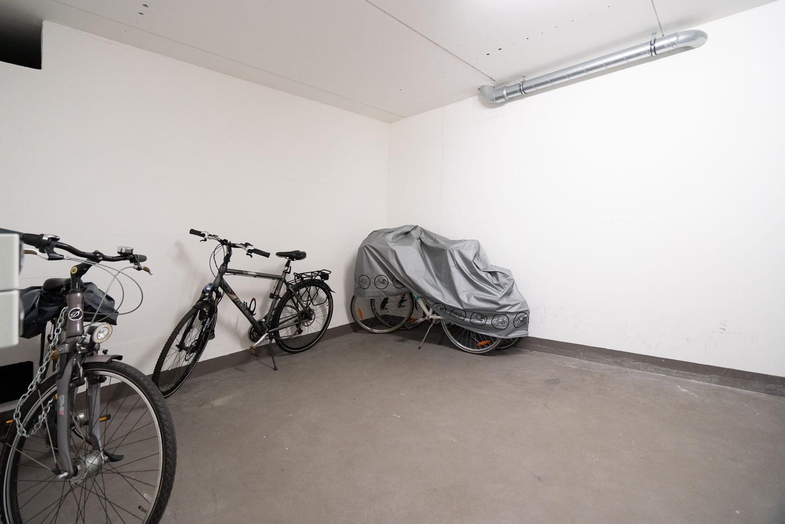 Tiefgarage mit drei Fahrrädern, eines davon zugedeckt.