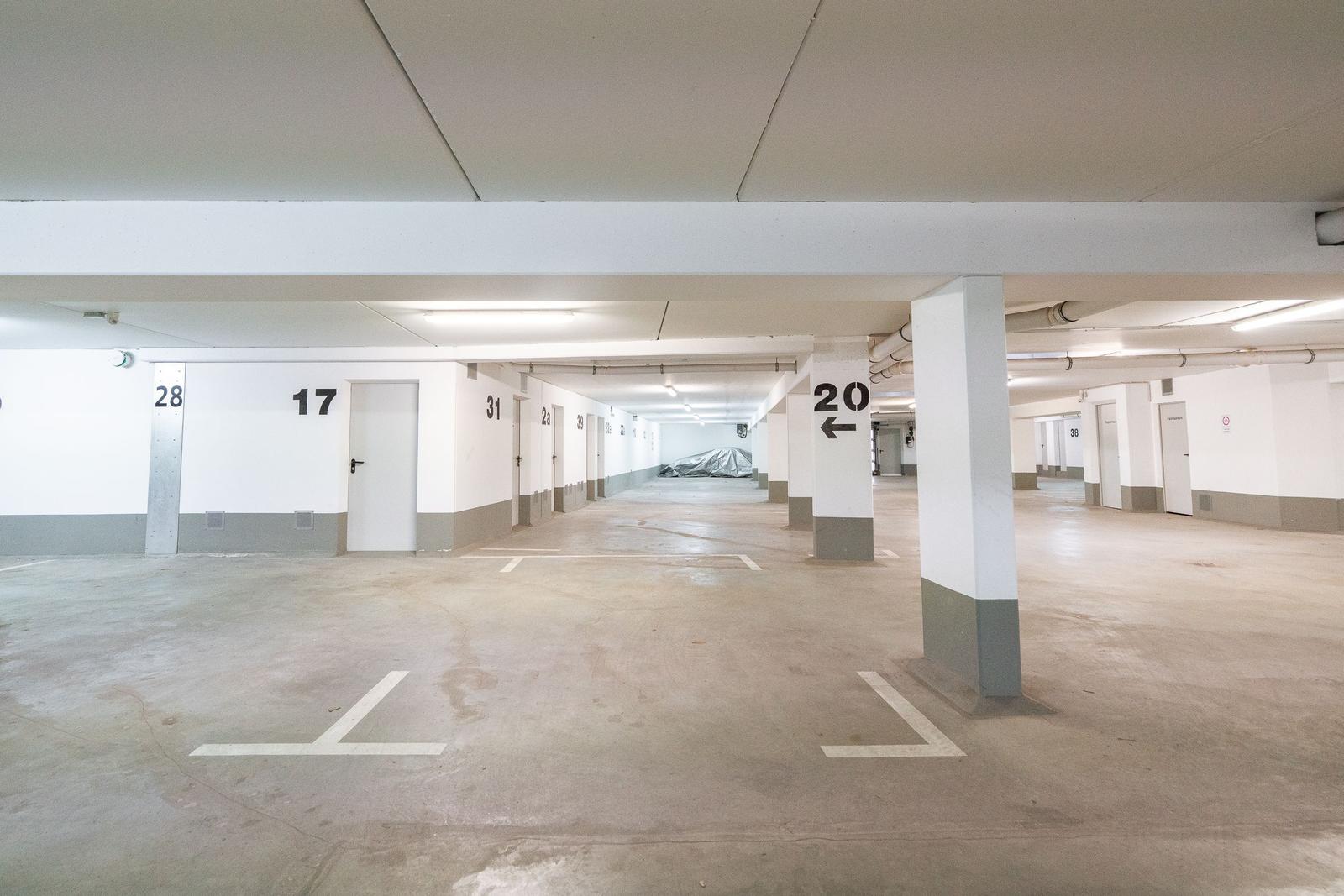 Untergeschoss-Parkhaus mit markierten Stellplätzen und Türen zu Parkgaragen.