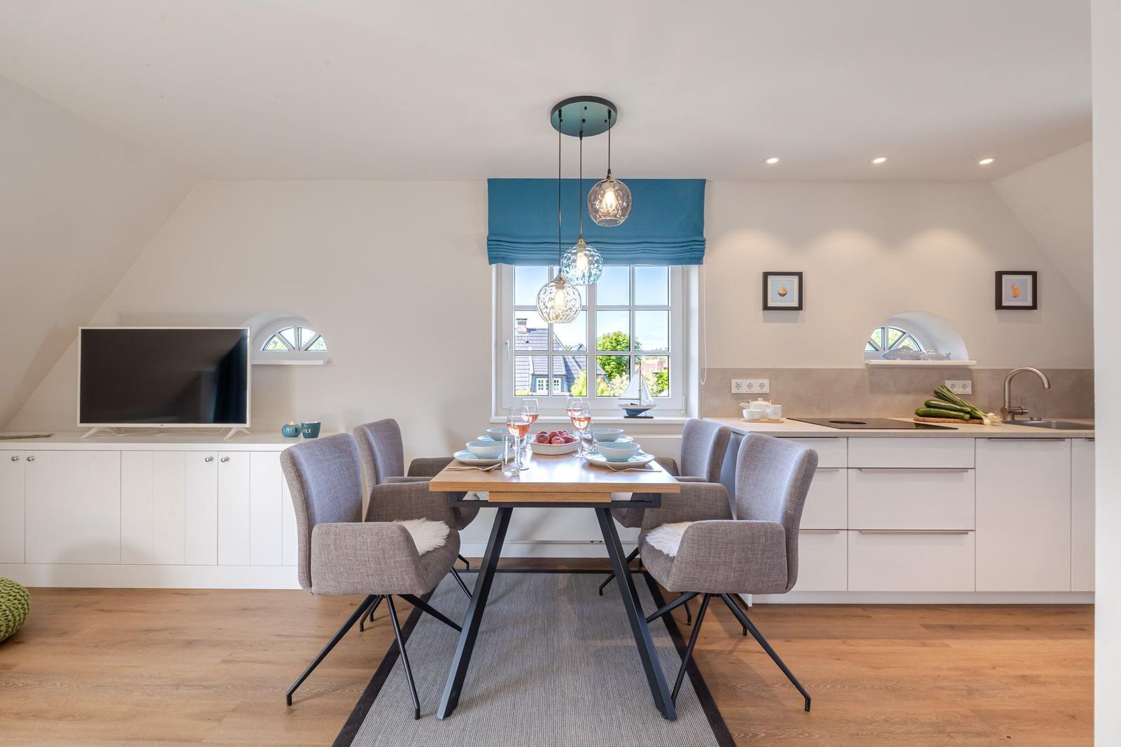 Dining area with table, chairs, and window. Kitchen with worktop and sink.